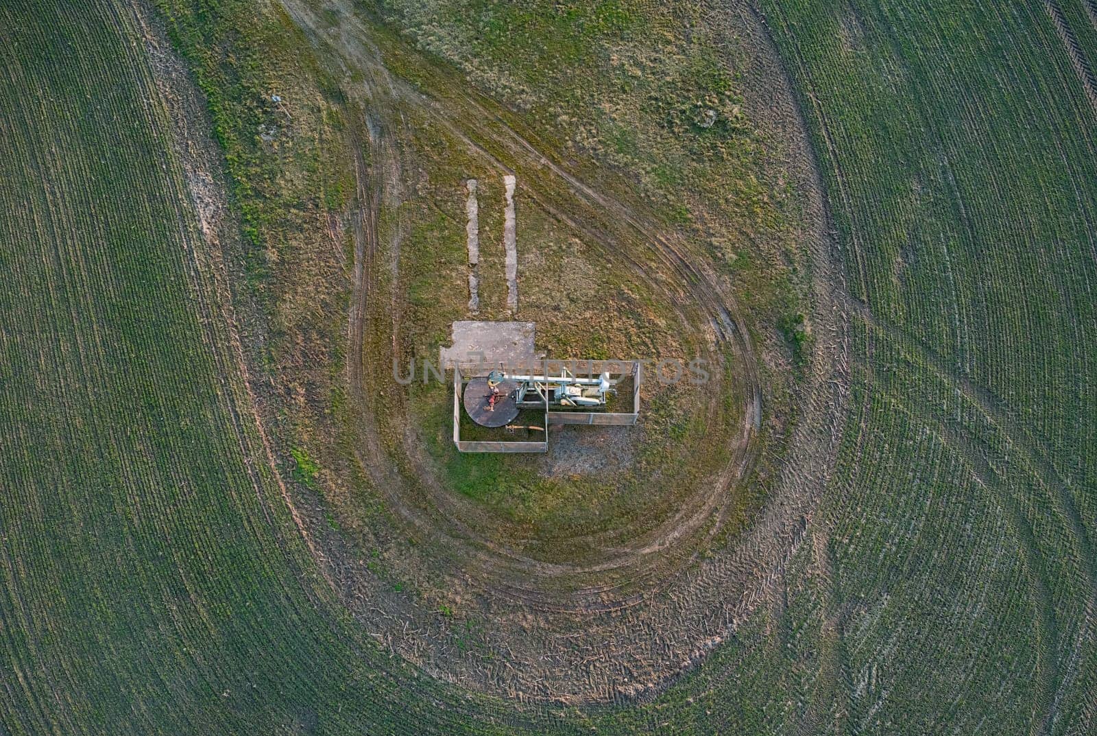 Aerial photo rocking pump located in Lower Saxony. The well is surrounded by a low mesh fence and is in a large open pasture.