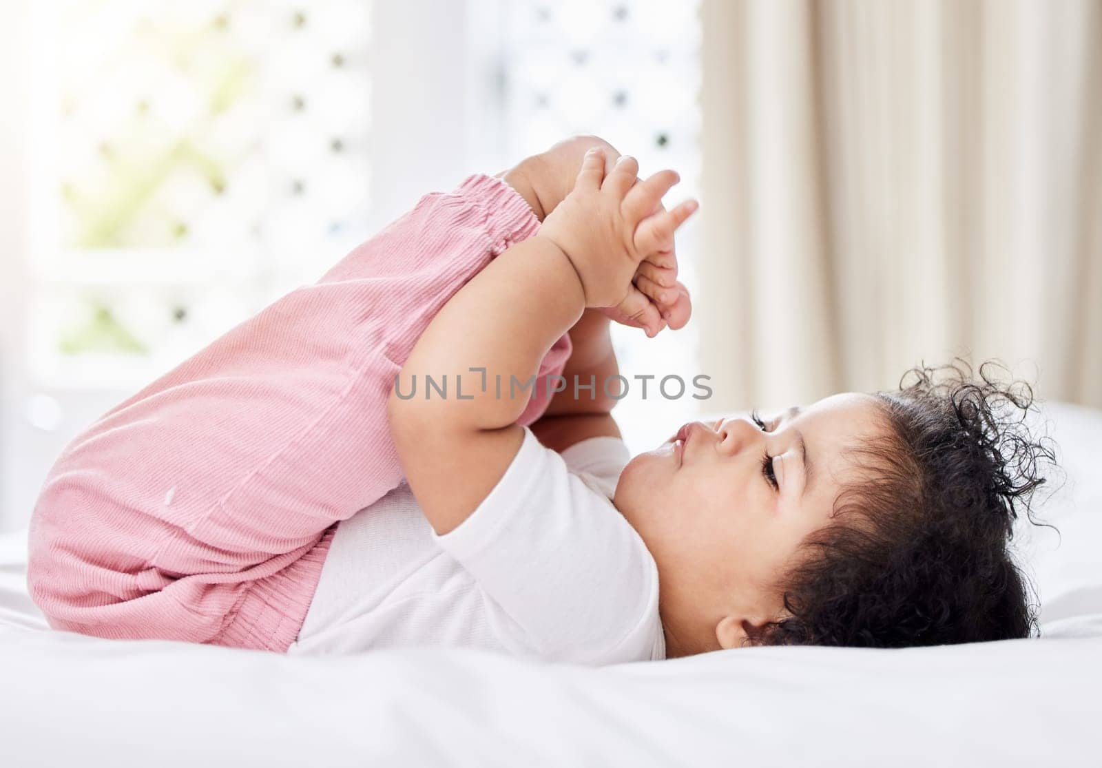 Baby, feet and hands with curiosity in bedroom for motor skills, growth or development. Little girl, toddler and grab of toes, looking and playing with excitement, discovery and milestone in home.