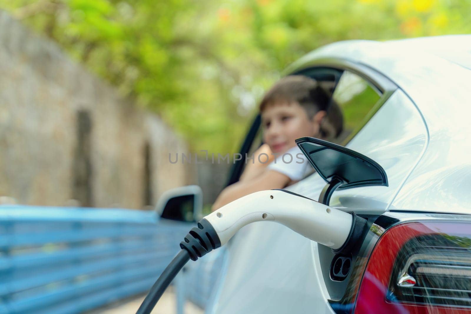 EV car recharge battery from EV charging station with blur boy, Perpetual by biancoblue