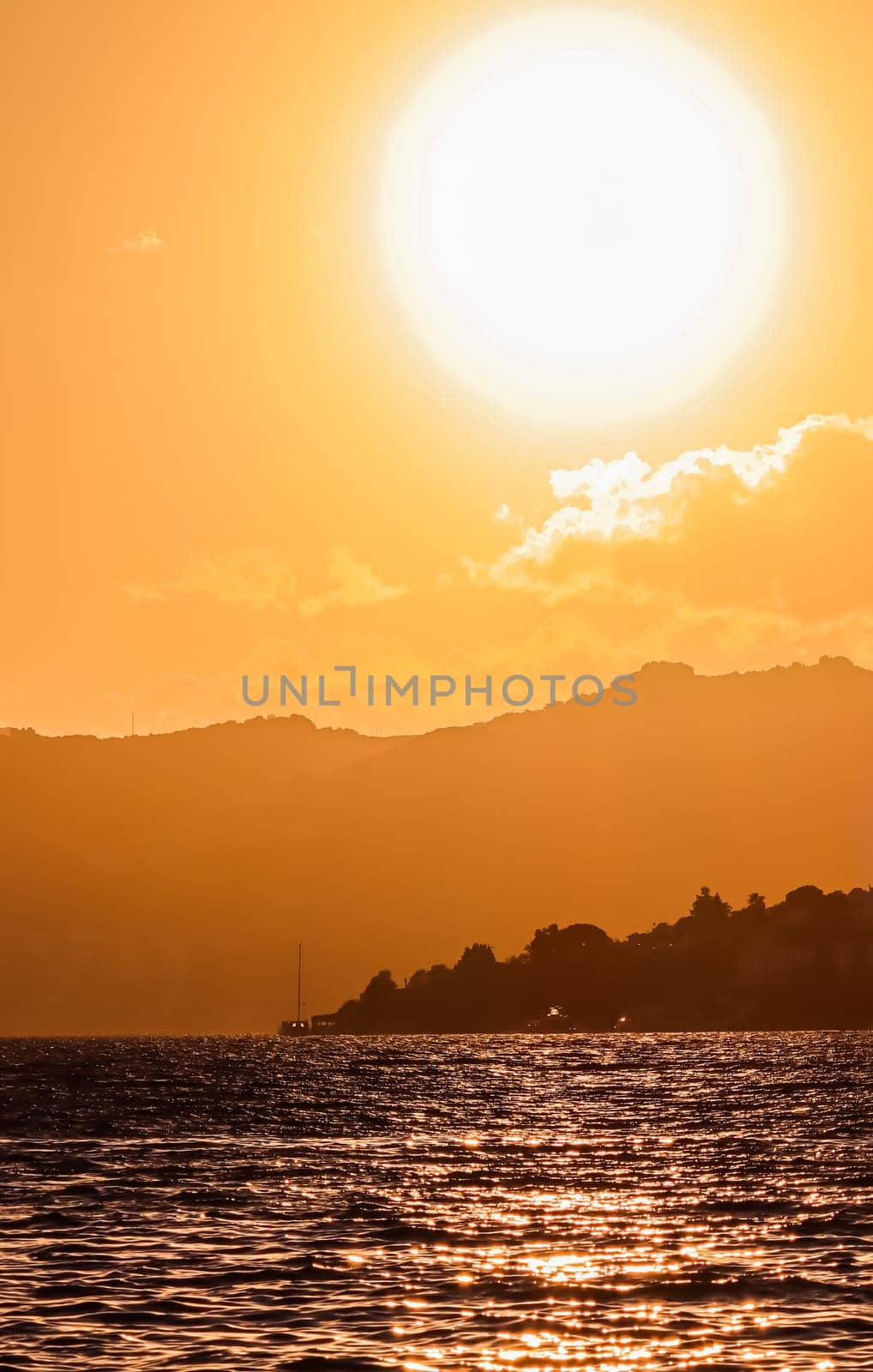 Beautiful sunset on the coast of the Aegean Sea with mountains and boats. Summer vacation and coastal nature concept