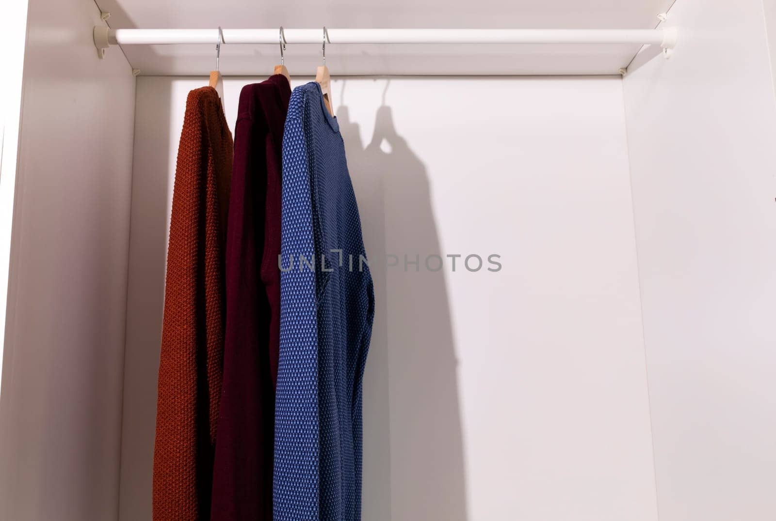 Hanging Men's Knitted Sweater or Cardigan in Closet, Stylish Male Casual Warm Cotton Clothes on Hangers in Wardrobe. Copy Space For Text. Horizontal Plane High quality photo