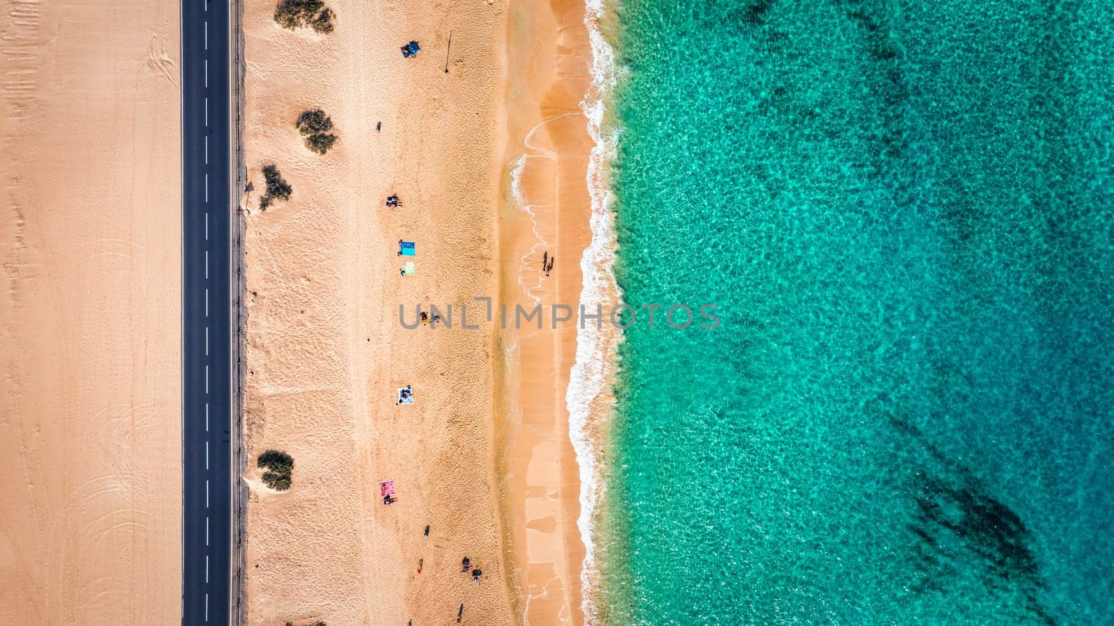 Aerial view of beach with asphalt road in Corralejo Park, Fuerteventura. Beach (Grandes Playas de Corralejo) and road on Fuerteventura, Canary Islands, Spain. Beautiful turquoise water and white sand.