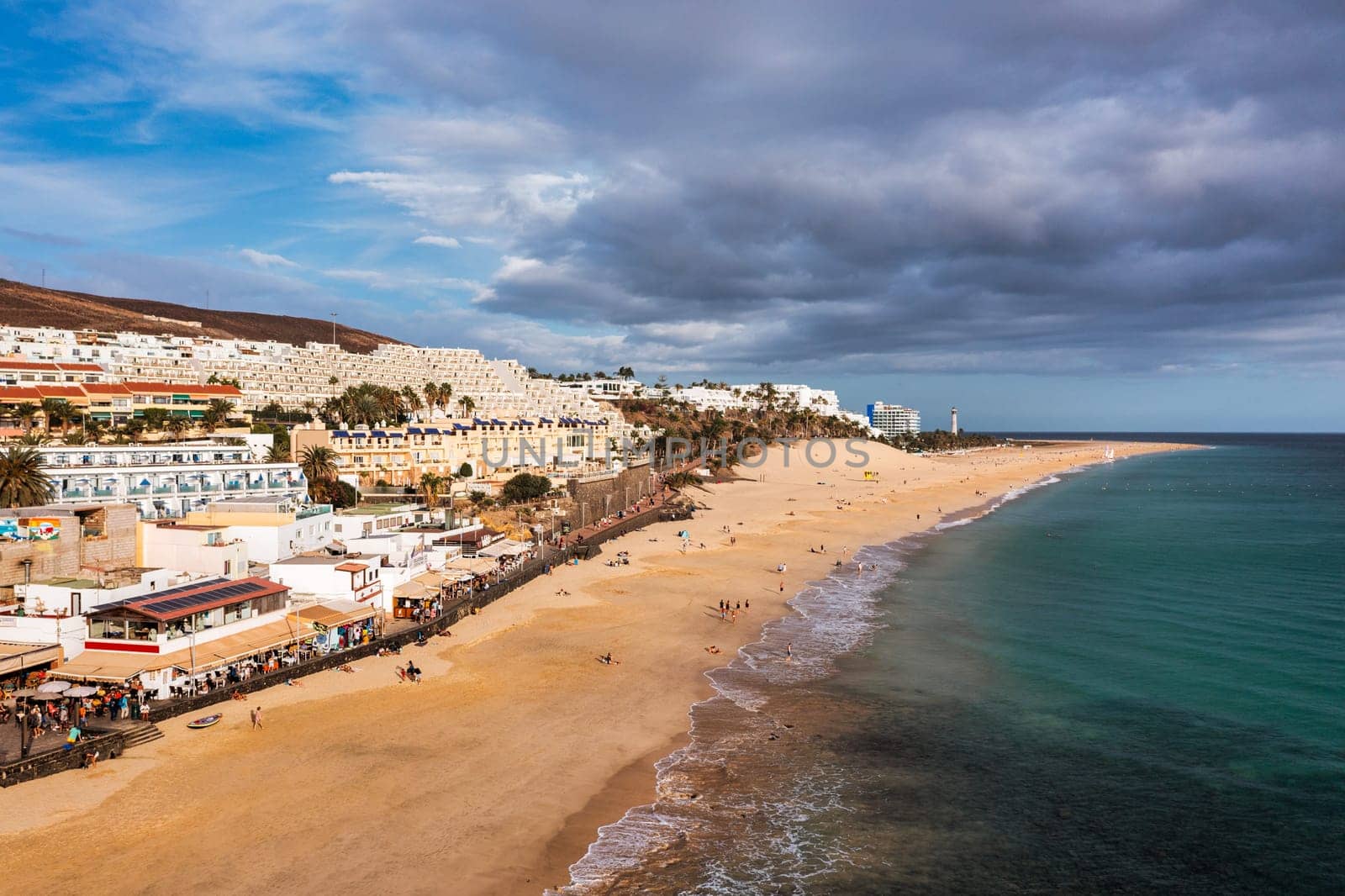 Aerial view of beach in Morro del Jable town (Morro Jable beach) on Fuerteventura island, Canary Islands, Spain. One of the best beach in the Canaries. Motorral lighthouse in distance.