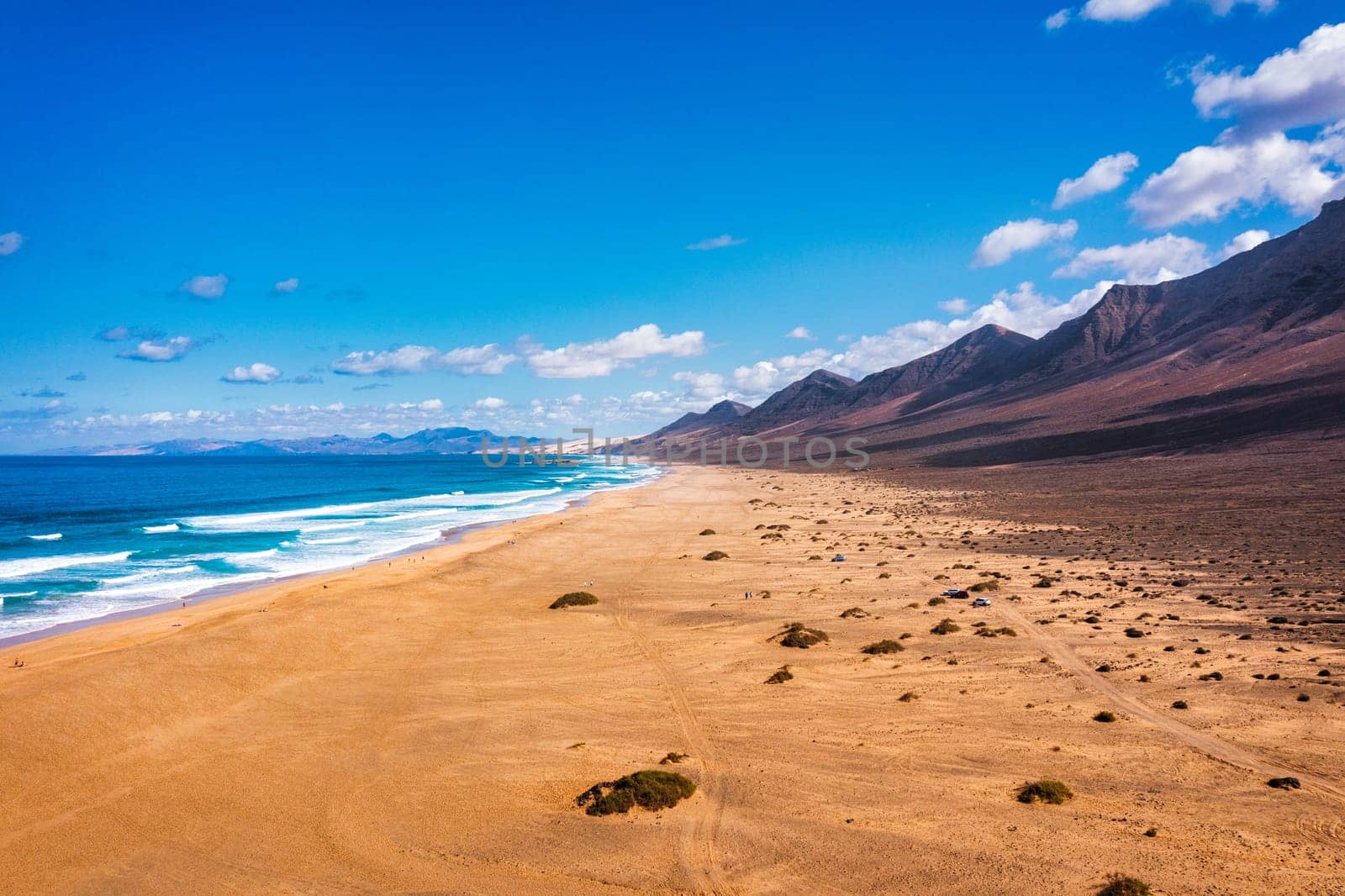 Amazing Cofete beach with endless horizon. Volcanic hills in the background and Atlantic Ocean. Cofete beach, Fuerteventura, Canary Islands, Spain. Playa de Cofete, Fuerteventura, Canary Islands.