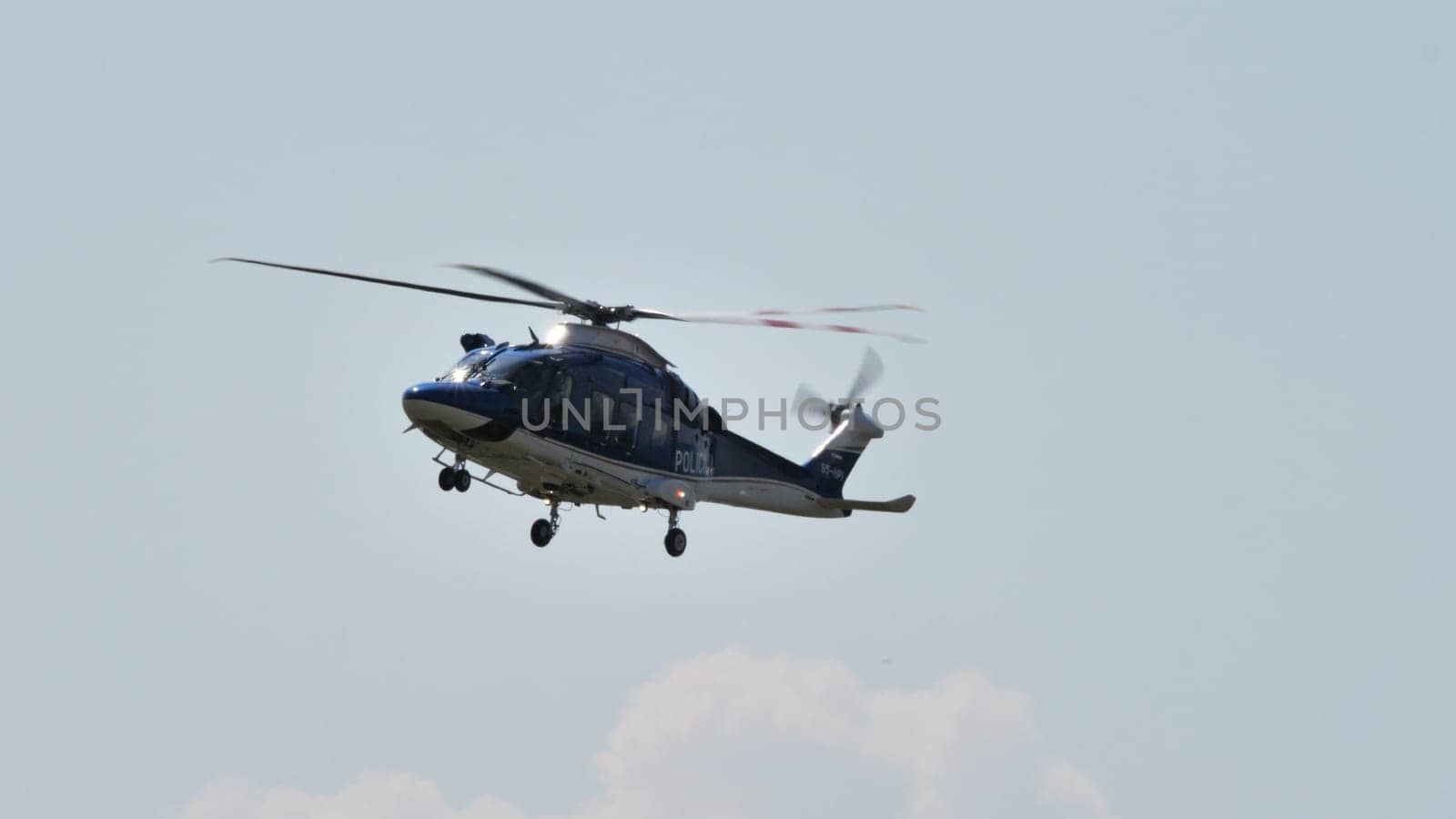 A police helicopter on a surveillance patrol against a clear blue sky, showcasing law enforcement in action.