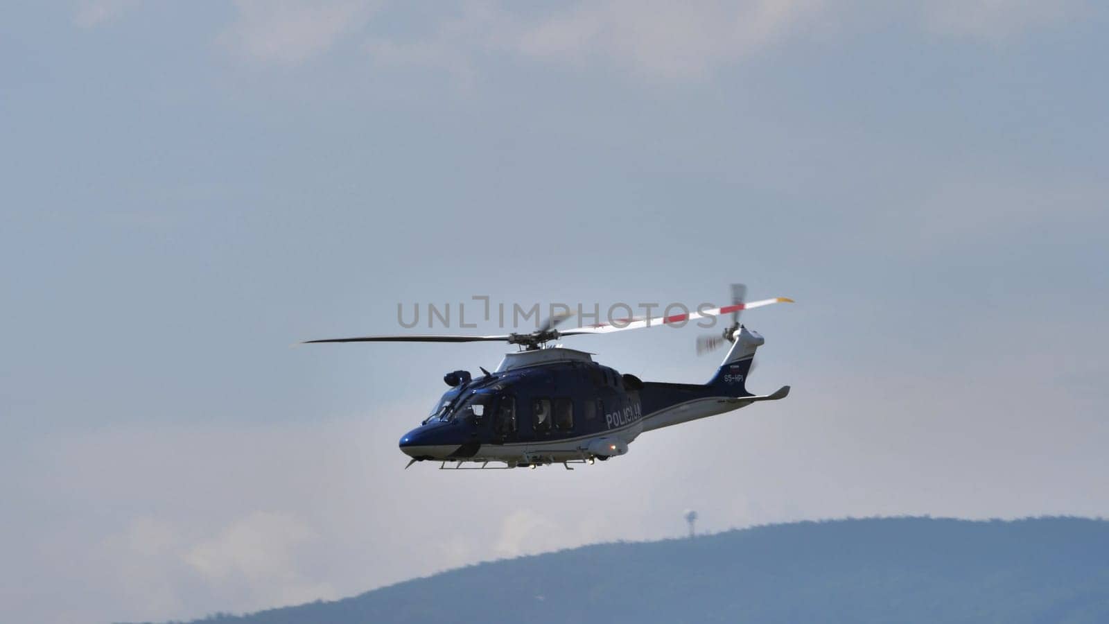 Blue police helicopter flying over a hazy landscape, showcasing law enforcement presence, with copy space.