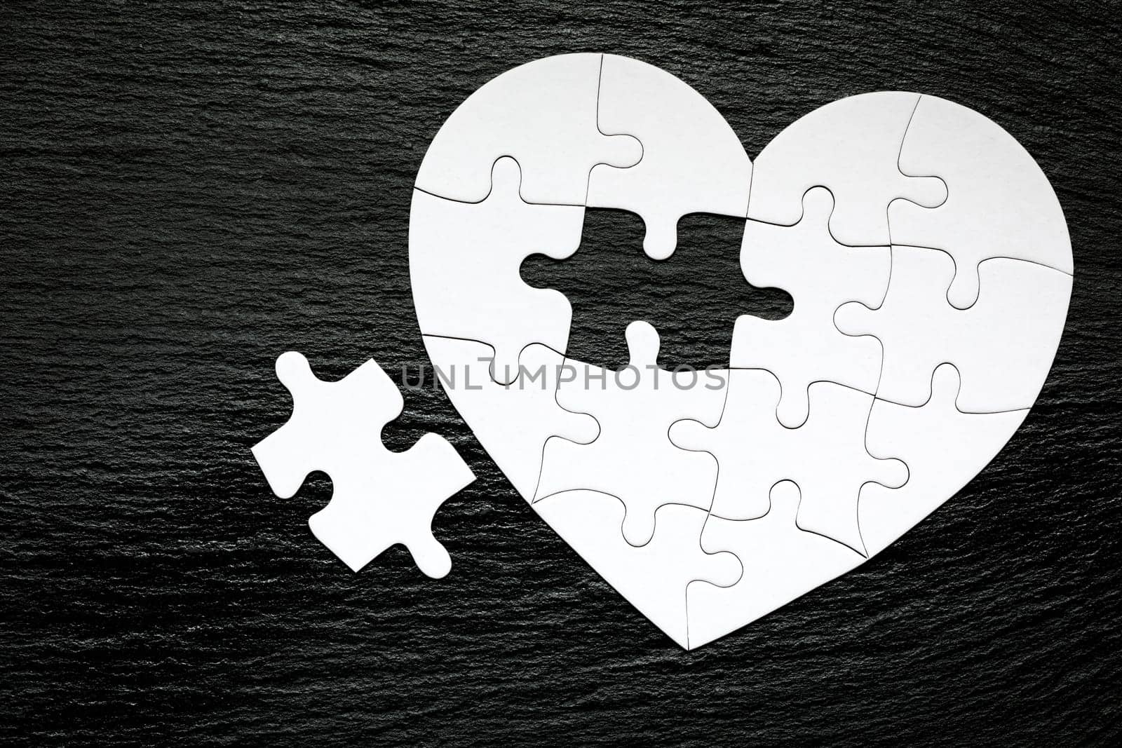 Heart-shaped jigsaw puzzle on color background. Puzzle heart on wooden background. A missing piece of the heart puzzle. Heart shape jigsaw puzzle. Puzzles in the shape of a heart. 