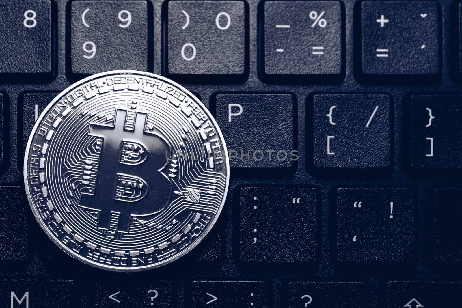 Bitcoin on compuer keyboard in background, symbol of electronic virtual money and mining cryptocurrency concept. Coin crypto currency bitcoin lies on the keyboard. Bitcoin on keyboard.
