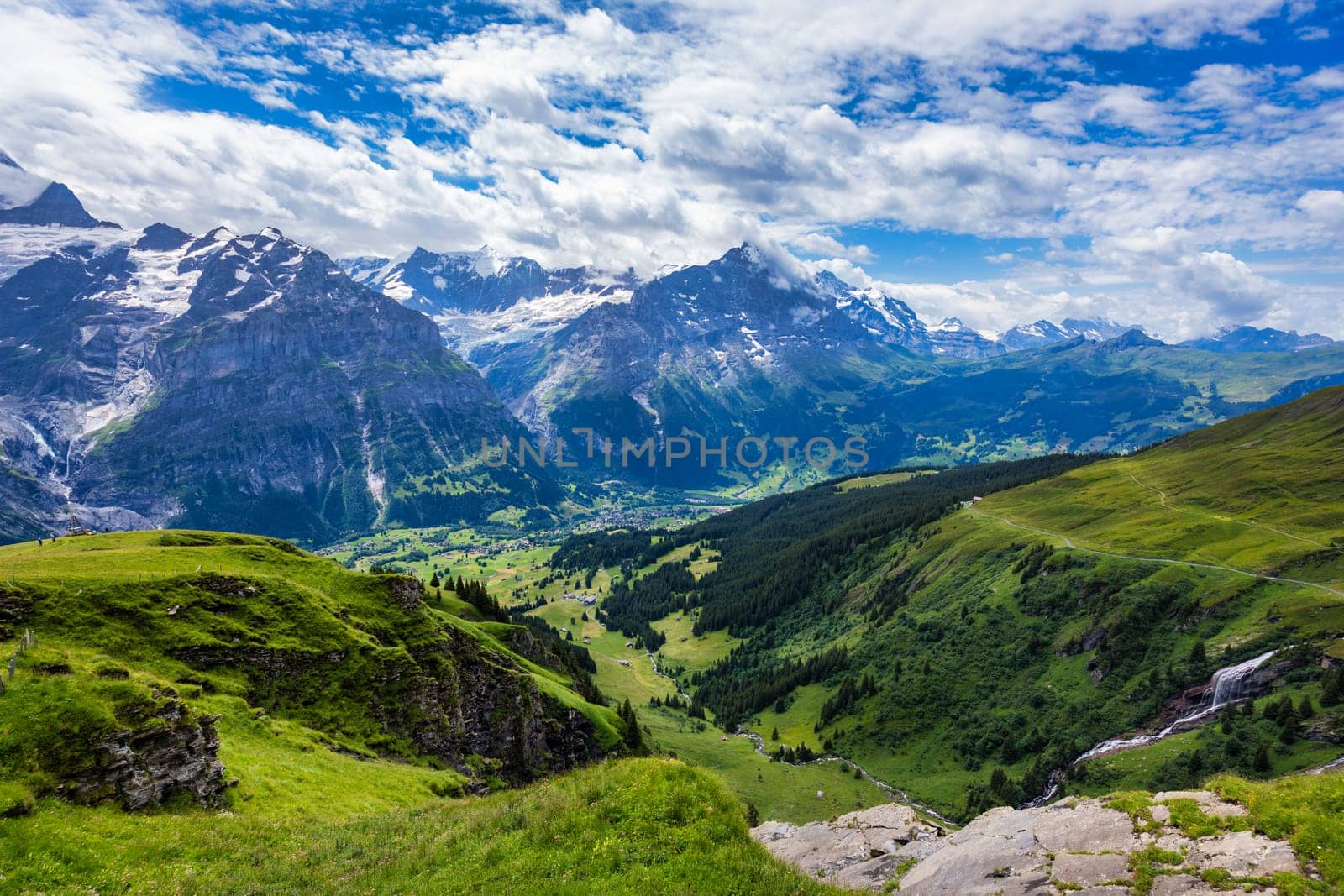 Grindelwald view and summer Swiss Alps mountains panorama landscape, green fields and high peaks in background, Switzerland, Bernese Oberland, Europe.