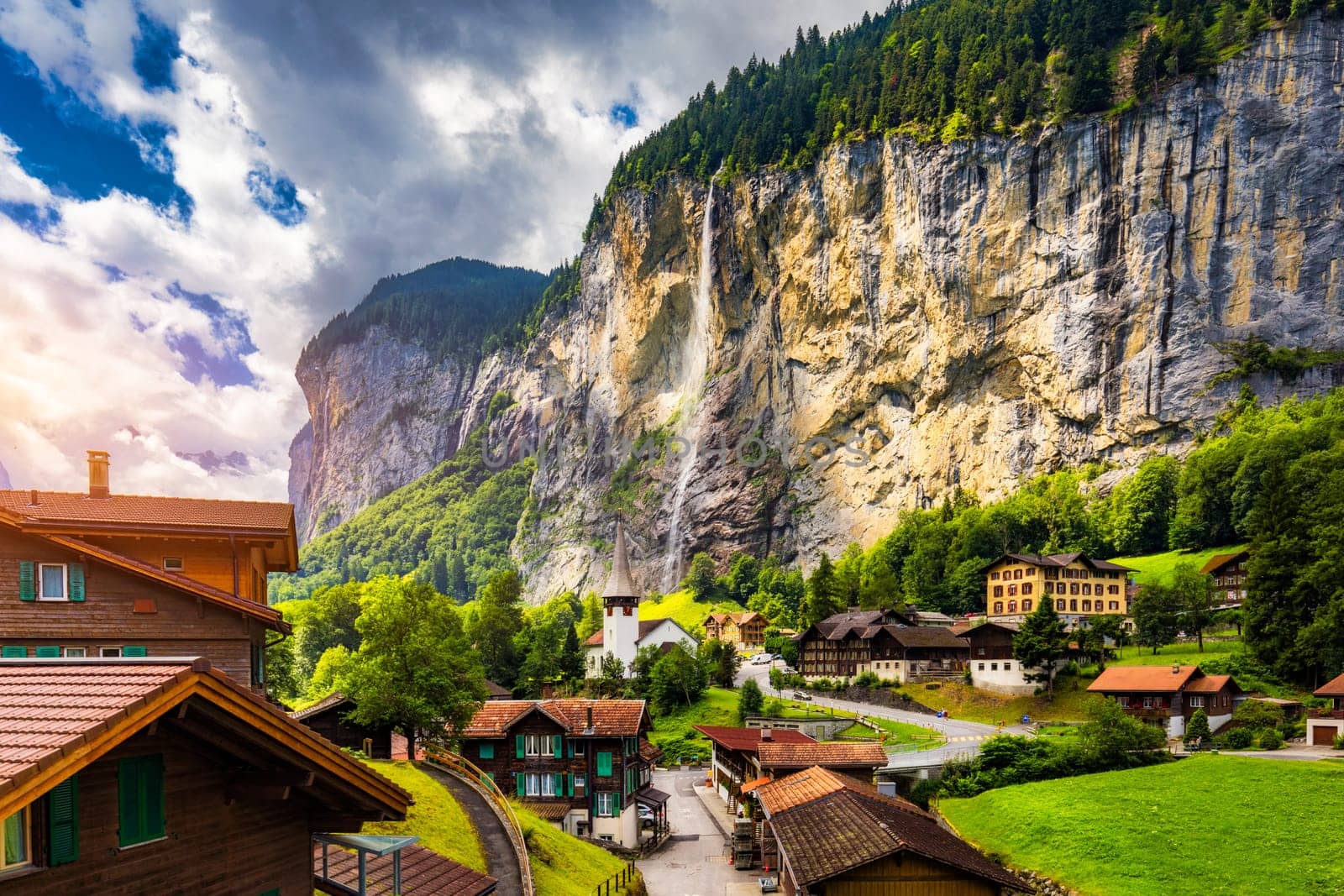 Amazing summer landscape of touristic alpine village Lauterbrunnen with famous church and Staubbach waterfall. Location: Lauterbrunnen village, Berner Oberland, Switzerland, Europe.