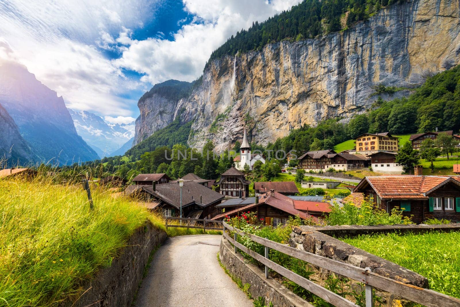 Amazing summer landscape of touristic alpine village Lauterbrunnen with famous church and Staubbach waterfall. Location: Lauterbrunnen village, Berner Oberland, Switzerland, Europe.