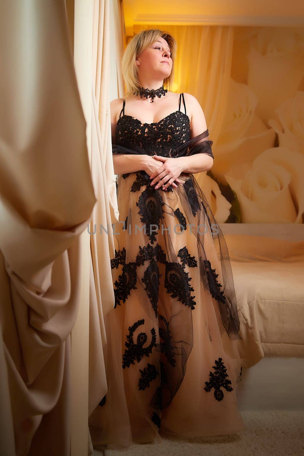 Portrait of beautiful elegant woman in in a royal dress indoors in nice room in evening time. A middle-aged adult lady in a romantic setting by keleny