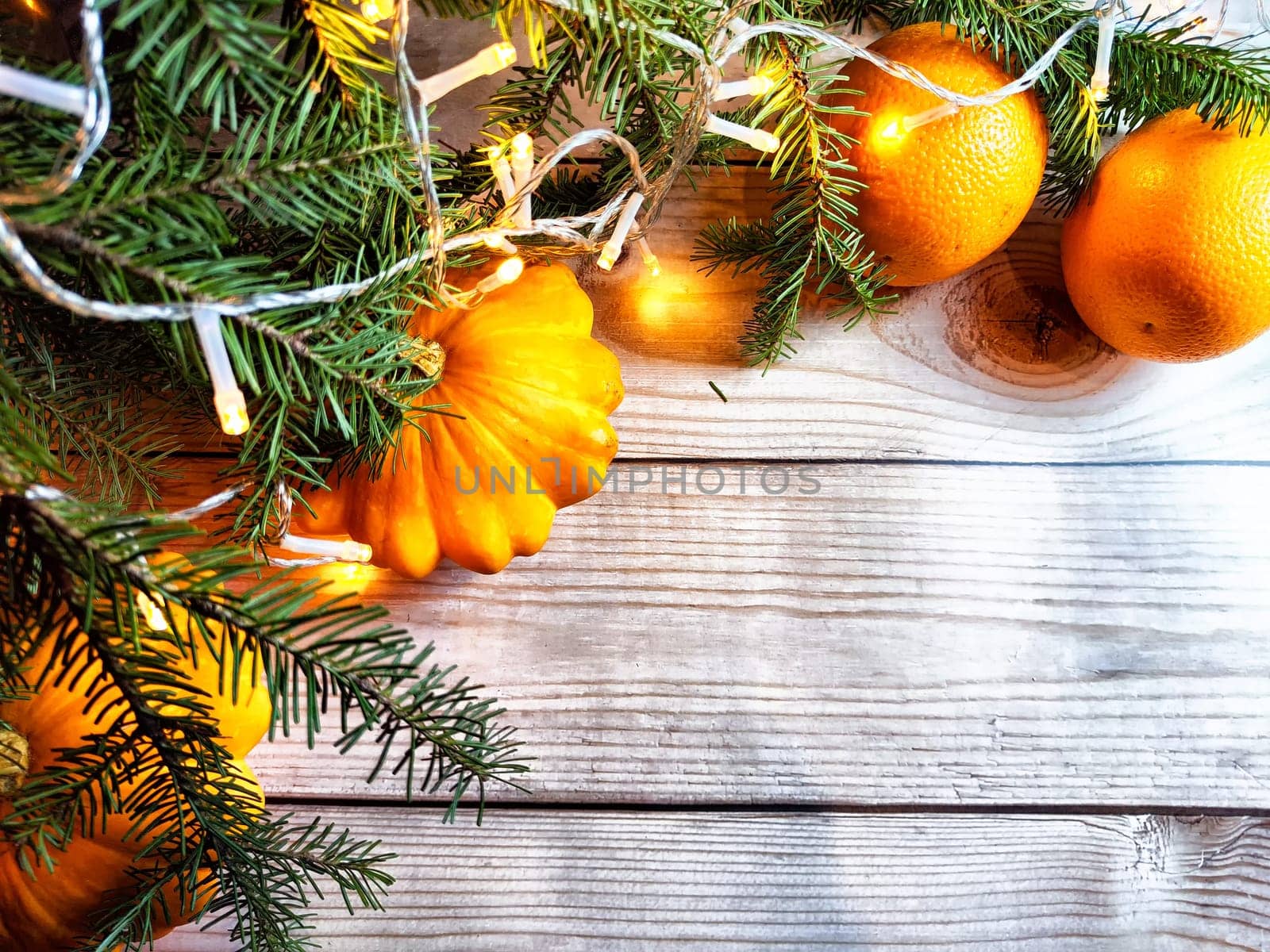 Festive decoration with bouquet and branches of spruce, bright glowing garlands, oranges on wooden background. Decor for Christmas and New Year. Abstract texture, frame, place for text and copy space