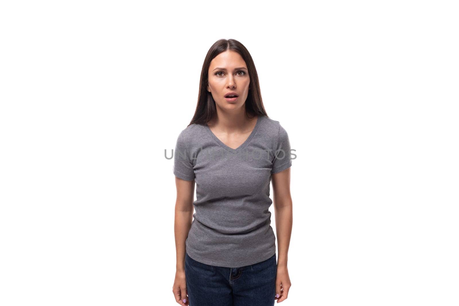 young surprised brunette promoter woman dressed in a gray t-shirt on a white background.