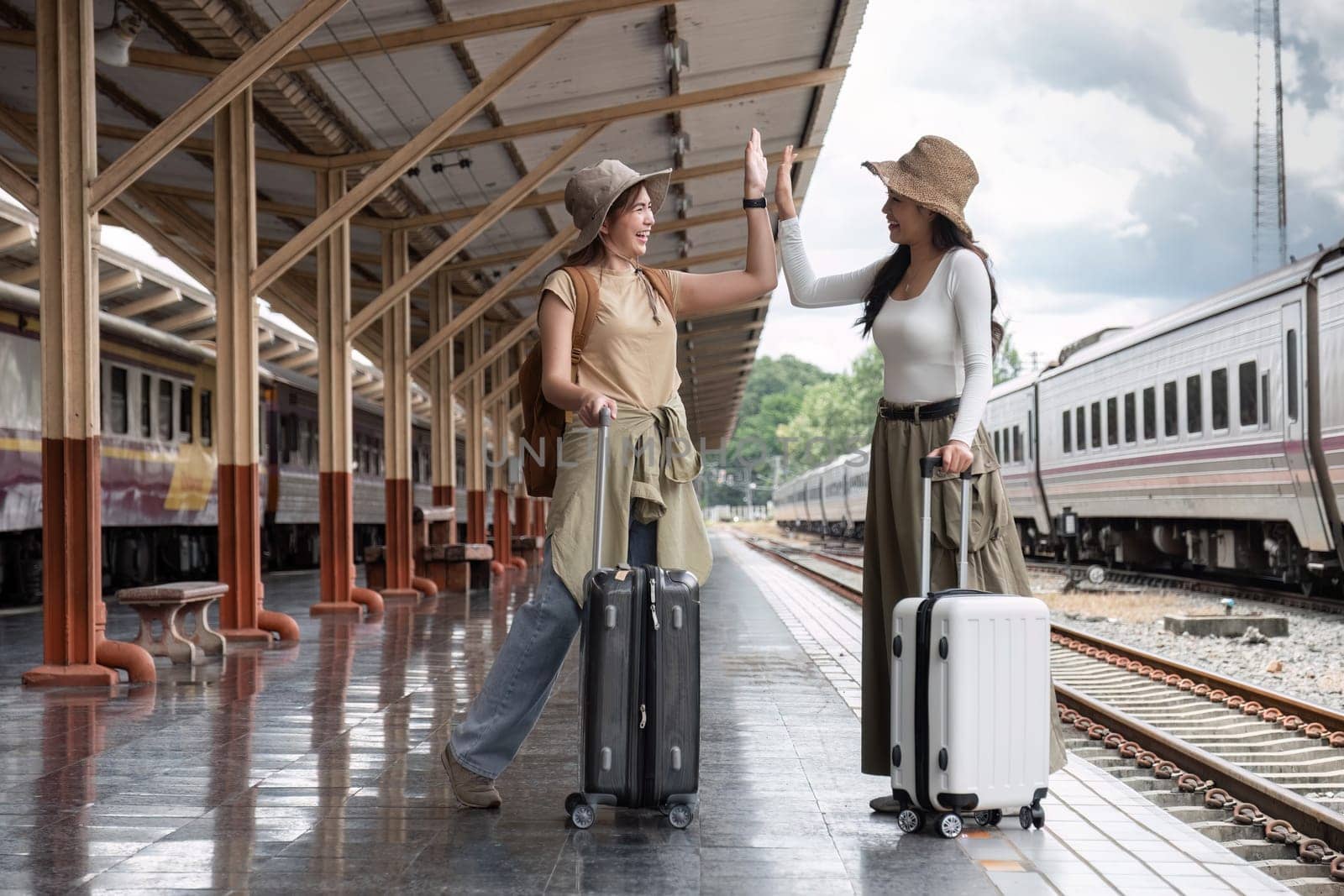 Young woman holding a suitcase waiting for a train at the train station while traveling on a weekend trip..