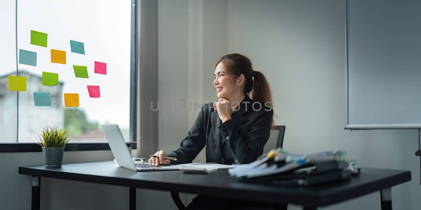 Business woman writing idea or tasks on sticky paper on wall, female team leader, executive manager, planning project, organize work by nateemee