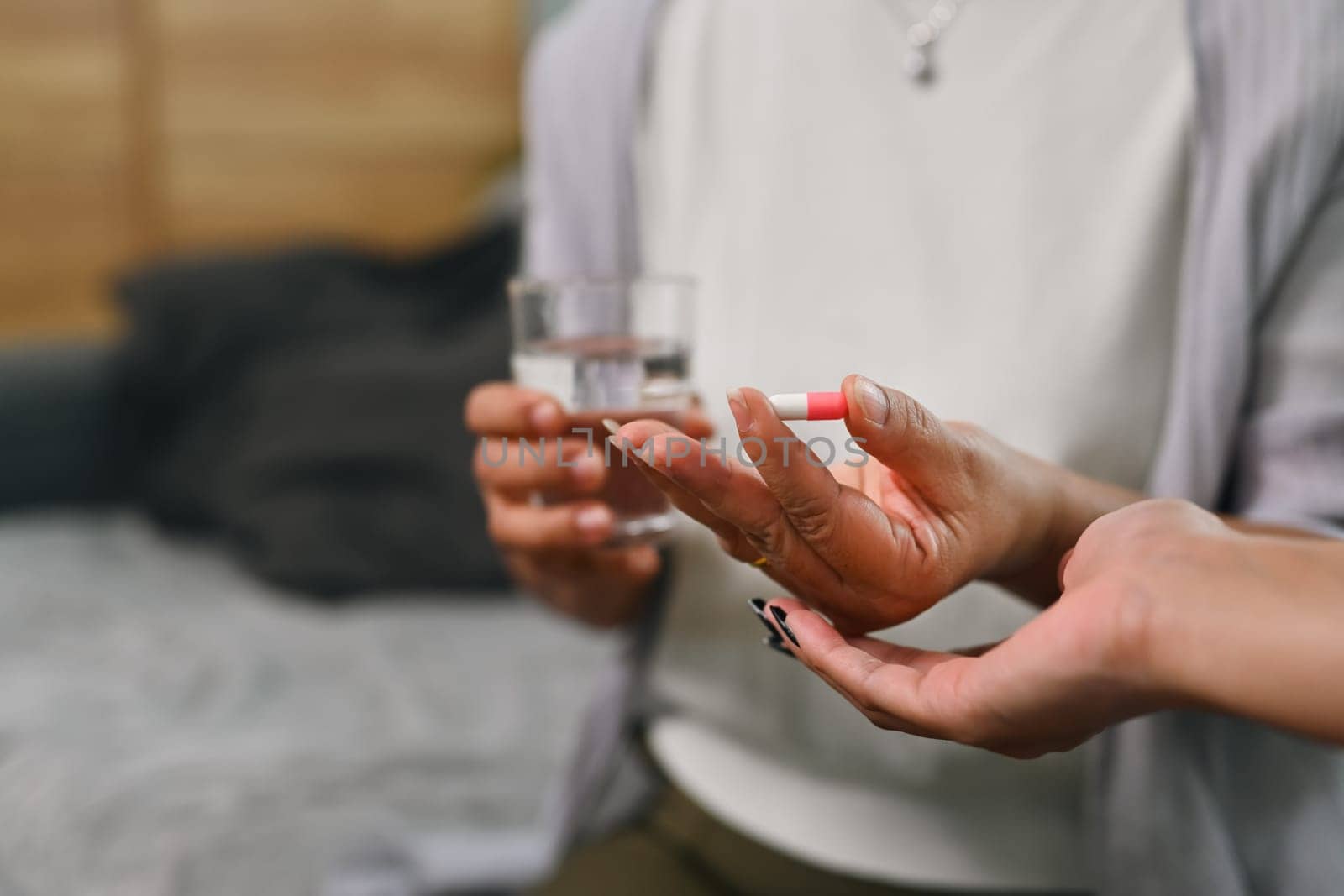 Close up mature woman holding pill and glass of water. Health care and daily meds concept.