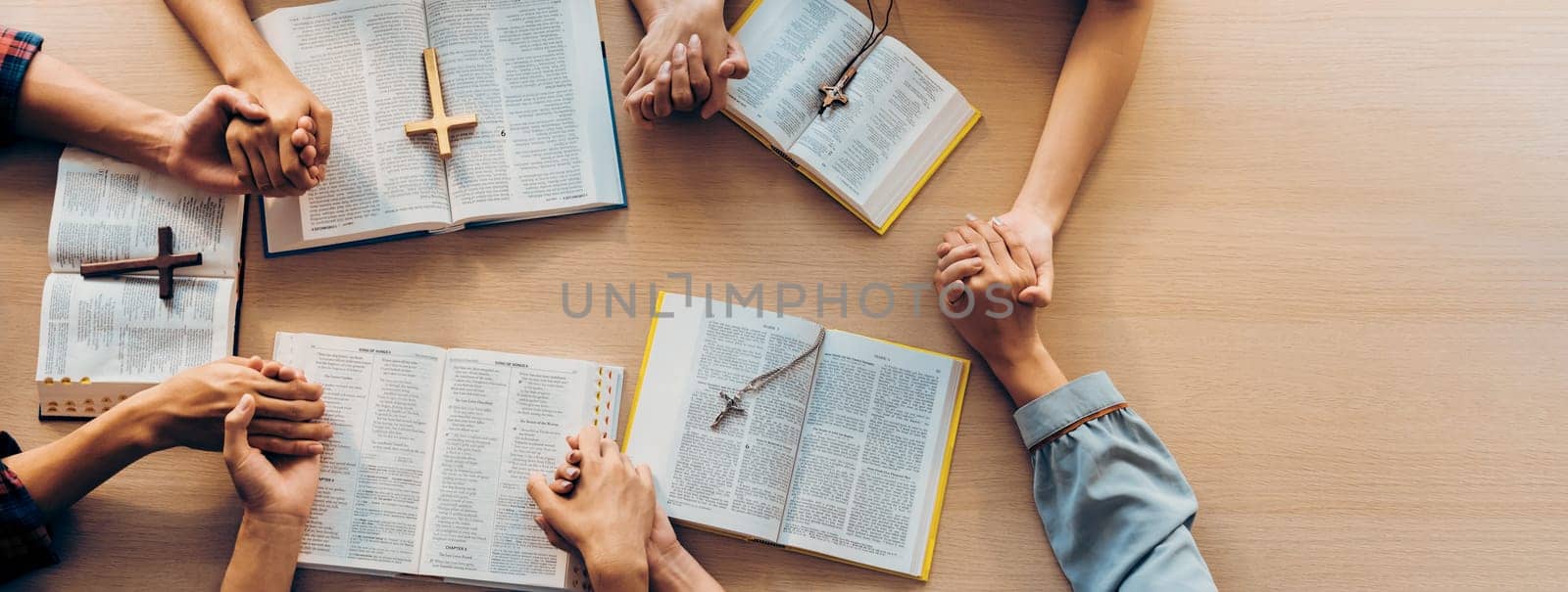 Cropped image of group of people praying together while holding hand on holy bible book at wooden church. Concept of hope, religion, faith, christianity and god blessing. Top view. Burgeoning.