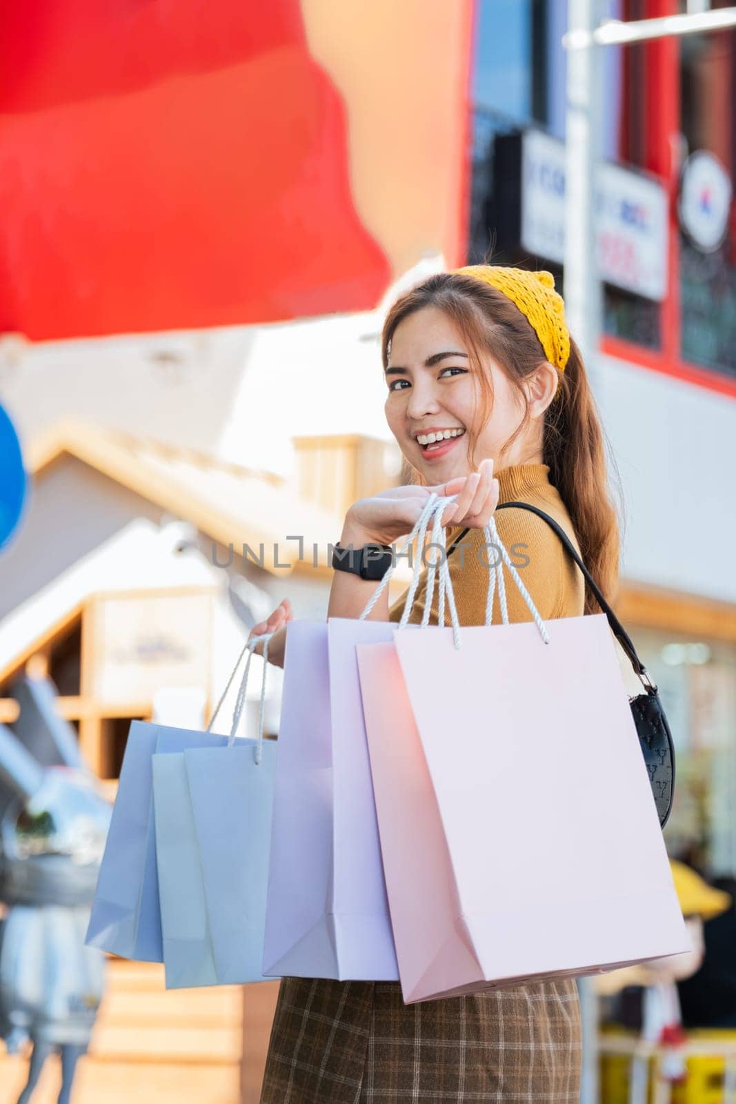 Happy beautiful young stylish woman with shopping bag while walking come out of mall on holiday.