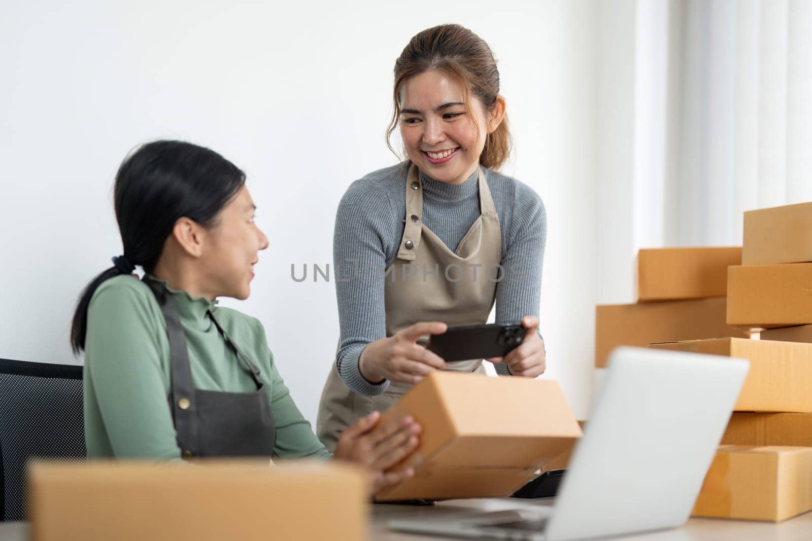 Small business SME owner, Two young Asian business owner woman prepare parcel box and check online orders of product for deliver to customer, packaging, Shopping Online concept.