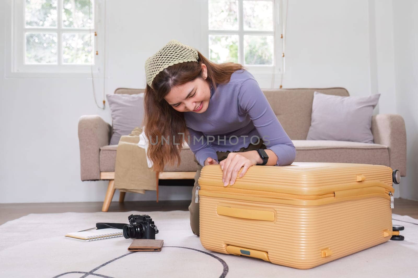 Attractive Asian woman packs her suitcase, packing her belongings, clothes and travel documents before going on vacation. Lifestyle concept by wichayada