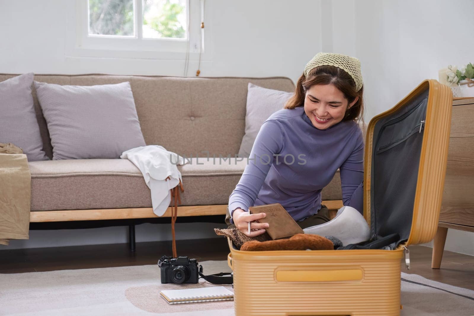 Attractive asian young woman packing a travel bag before going on holiday. Life style concept..