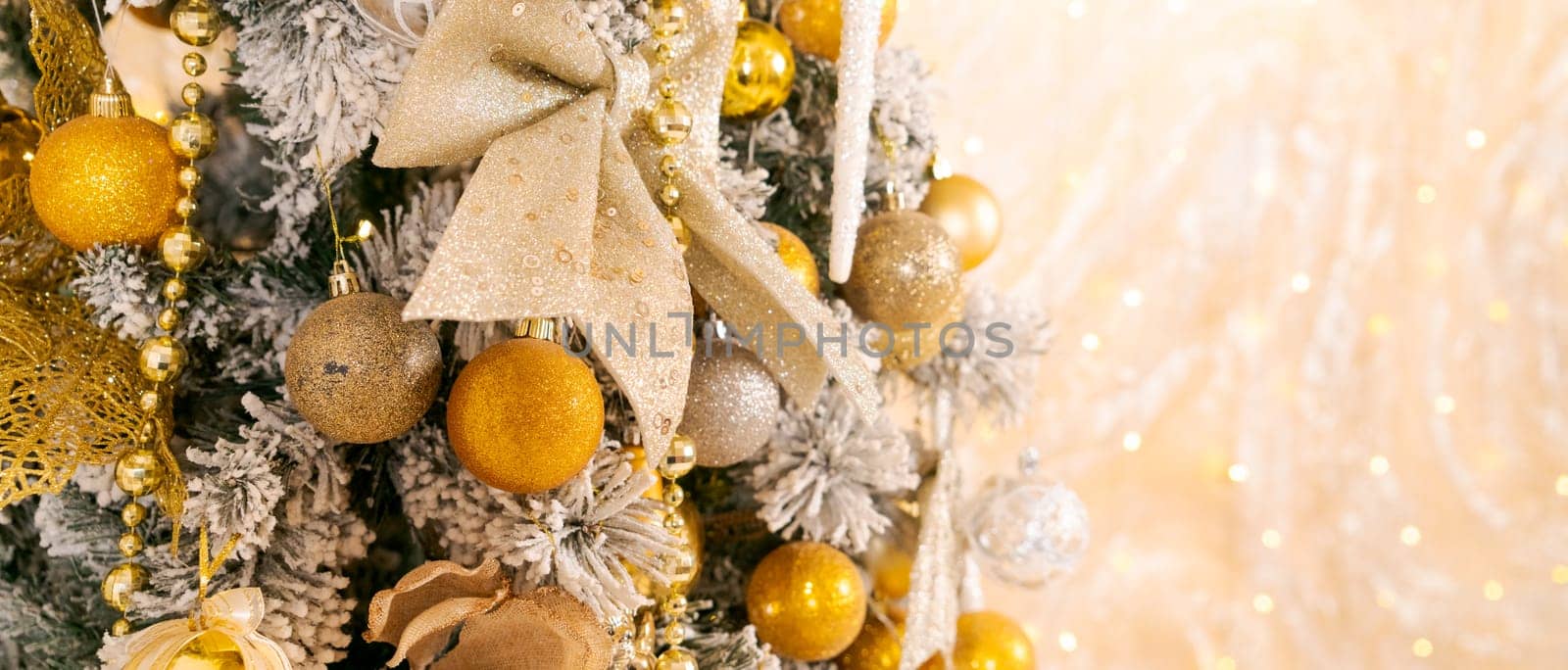 Christmas tree decorated with Golden balls toys on blurred, sparkling and fabulous fairy background with beautiful bokeh, copy space.