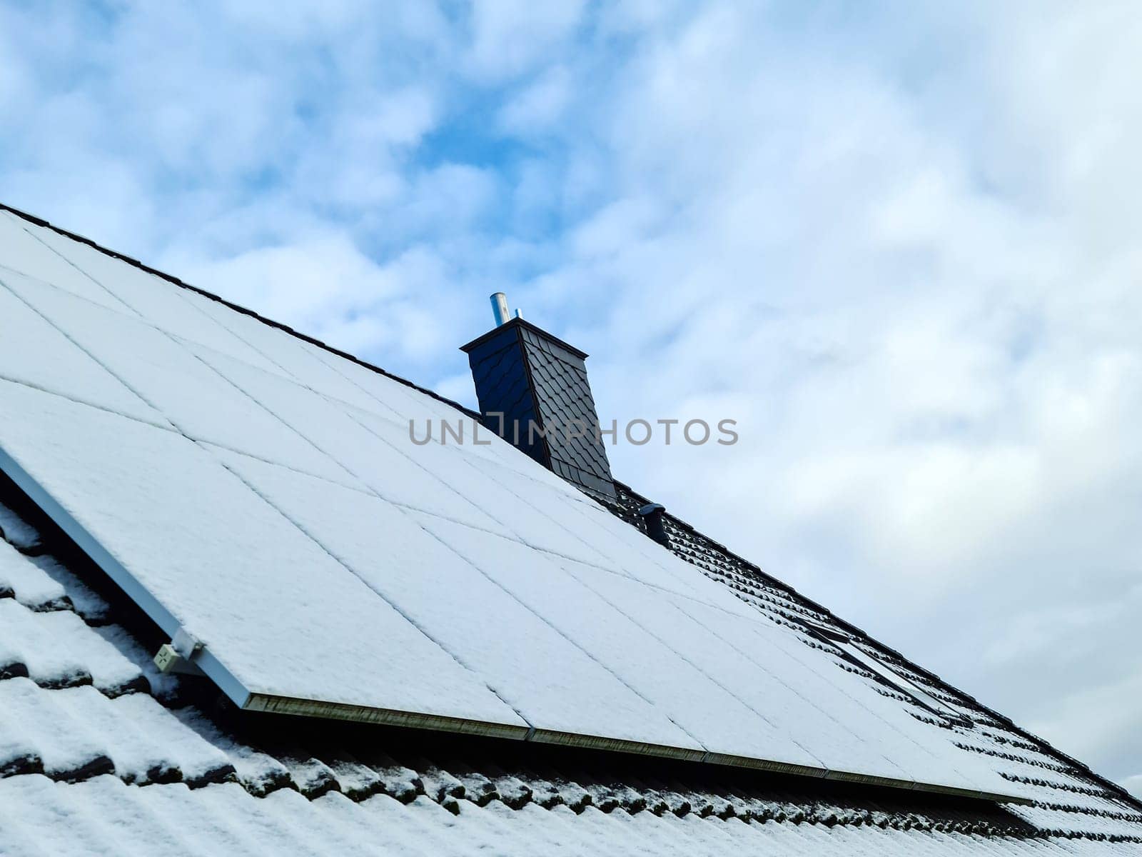 Snow covered solar panels producing clean energy on a roof of a residential house. by MP_foto71