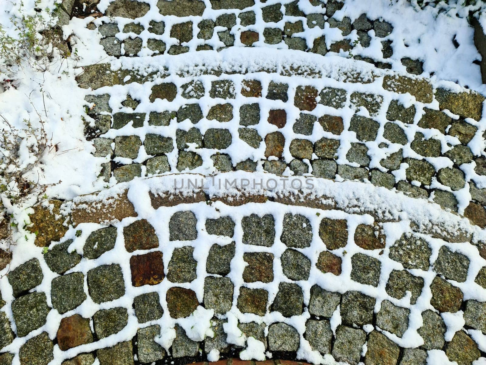 Surface of white snow on an old cobblestone way in winter