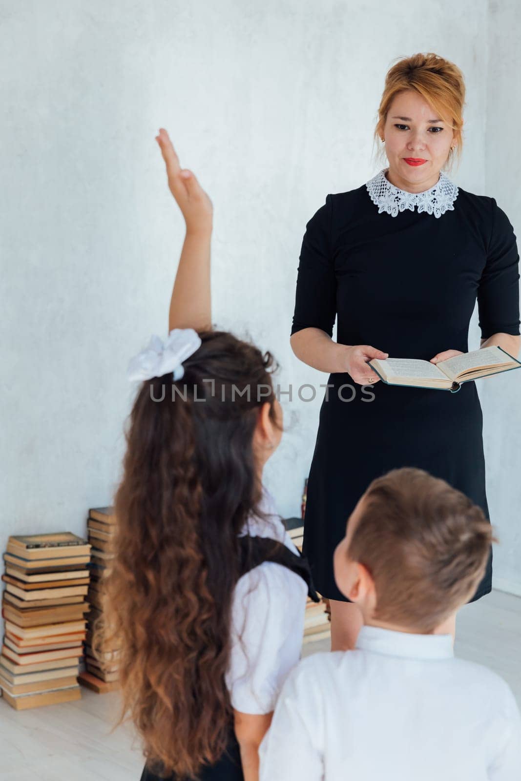Female teacher at lesson at school with children and books by Simakov