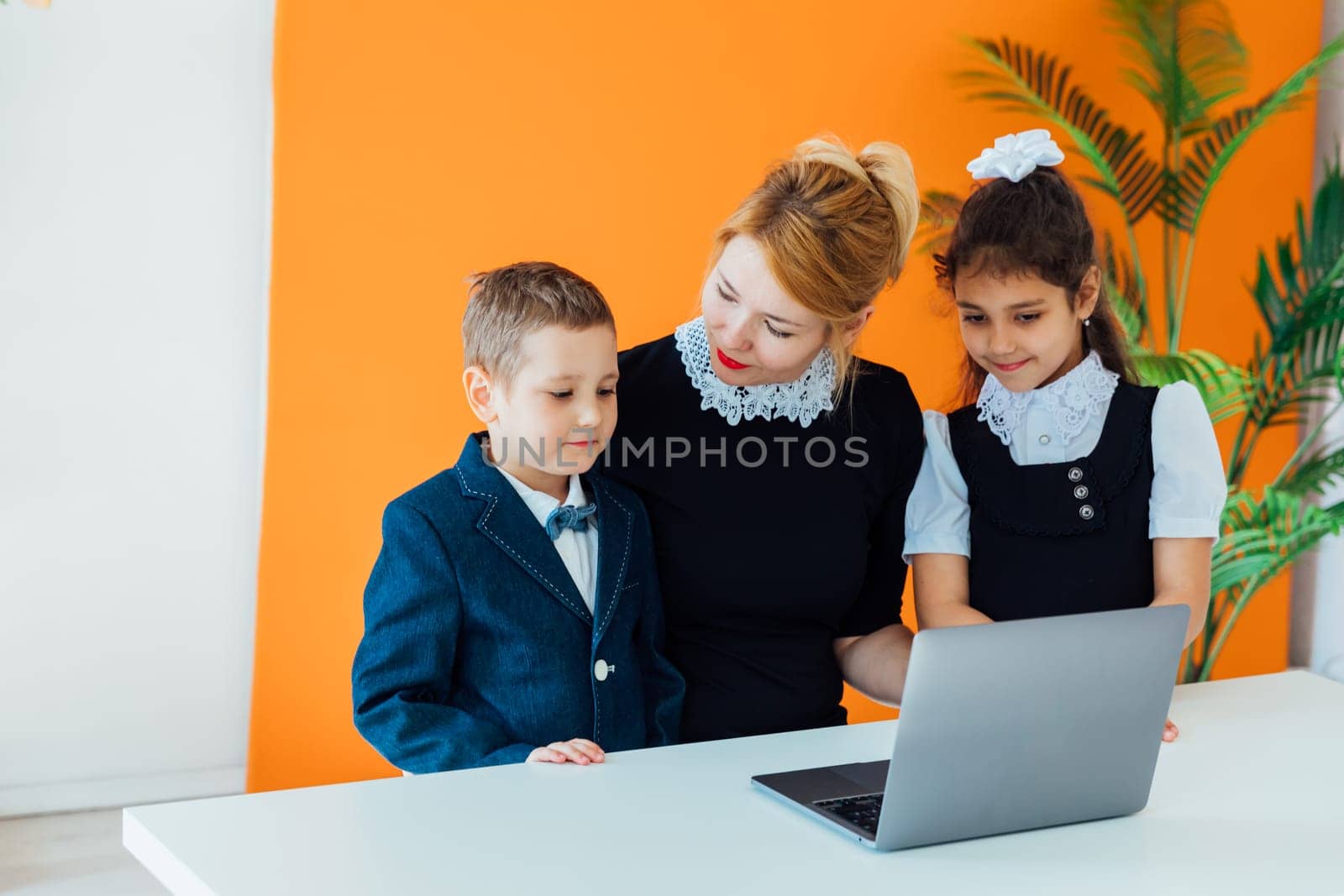 Teacher teaching boy and girl on computer at school by Simakov