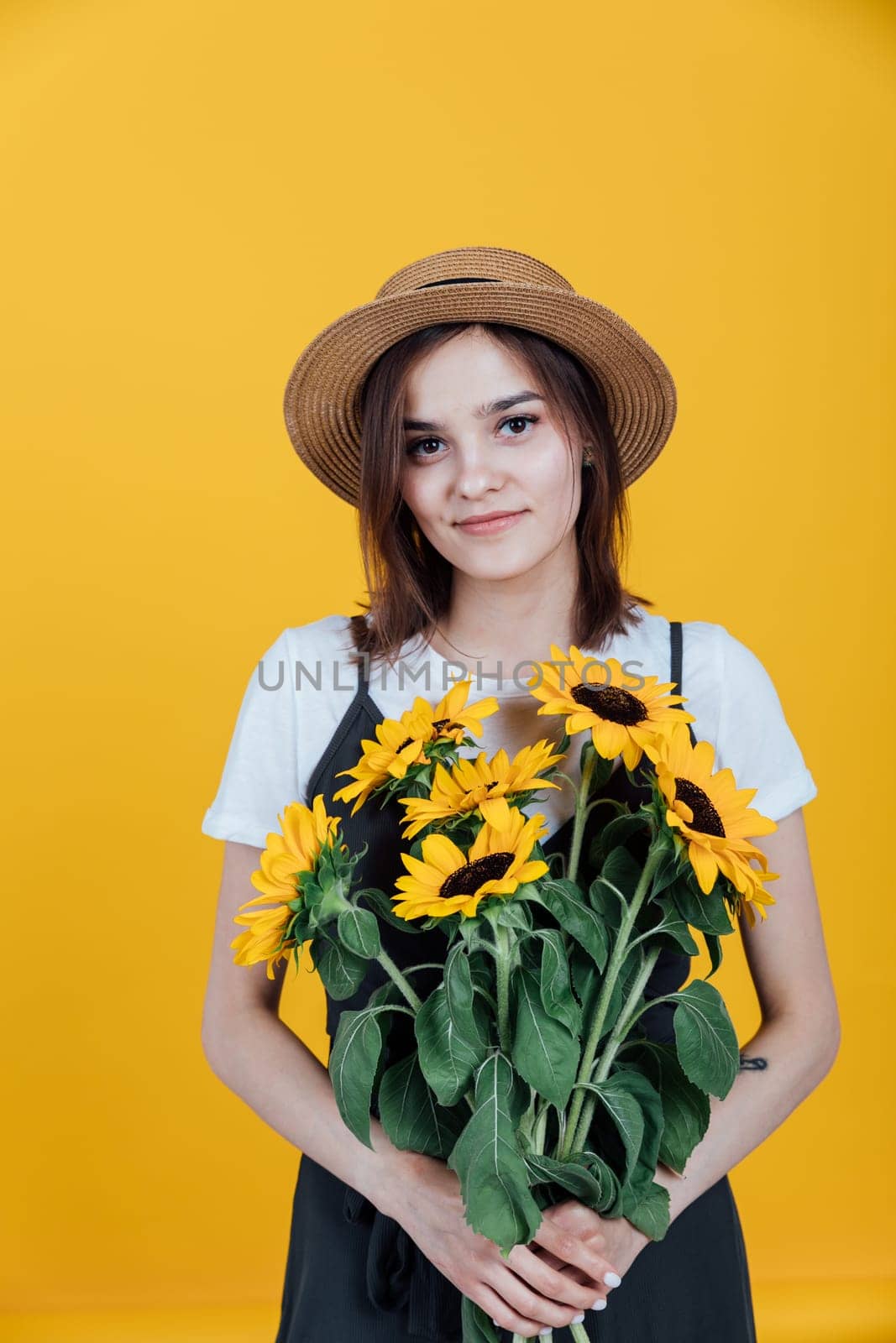 Woman in a hat with a bouquet of daisies on a yellow background by Simakov