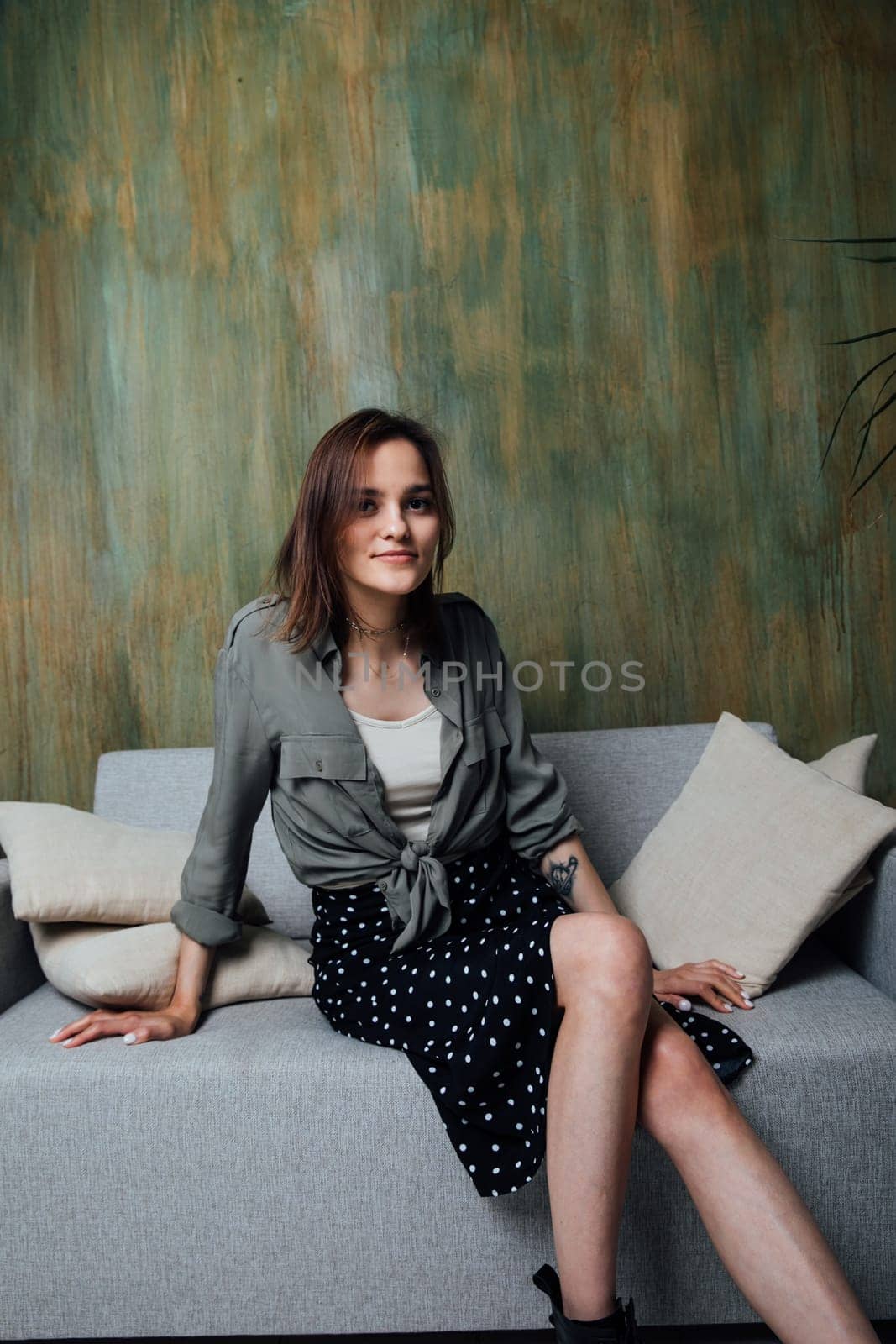Woman on grey sofa with pillows in room