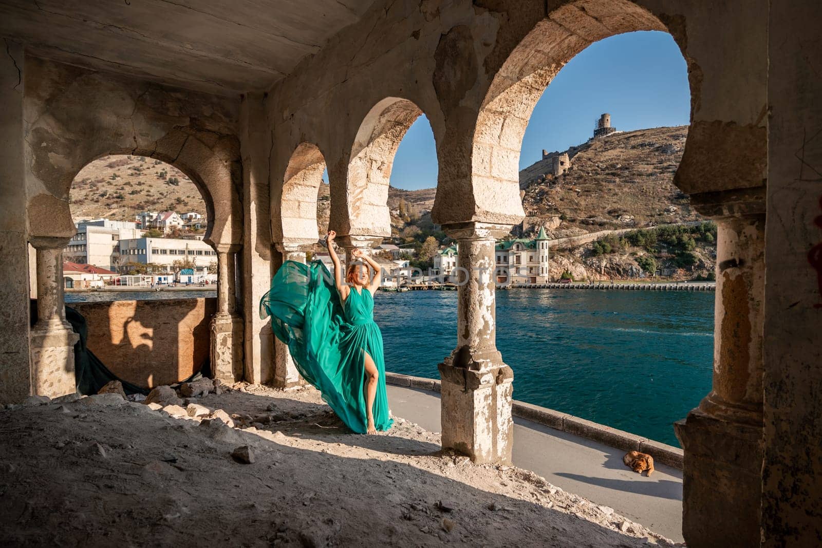 Woman dress sea columns. Rear view of a happy blonde woman in a long mint dress posing against the backdrop of the sea in an old building with columns. by Matiunina