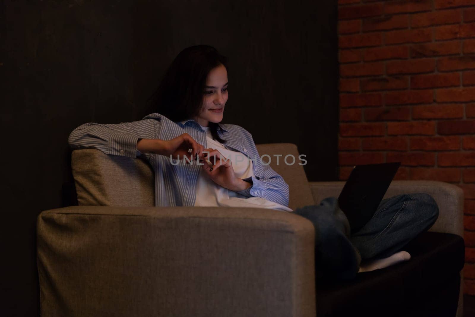 Woman sitting on sofa with computer chatting online job by Simakov