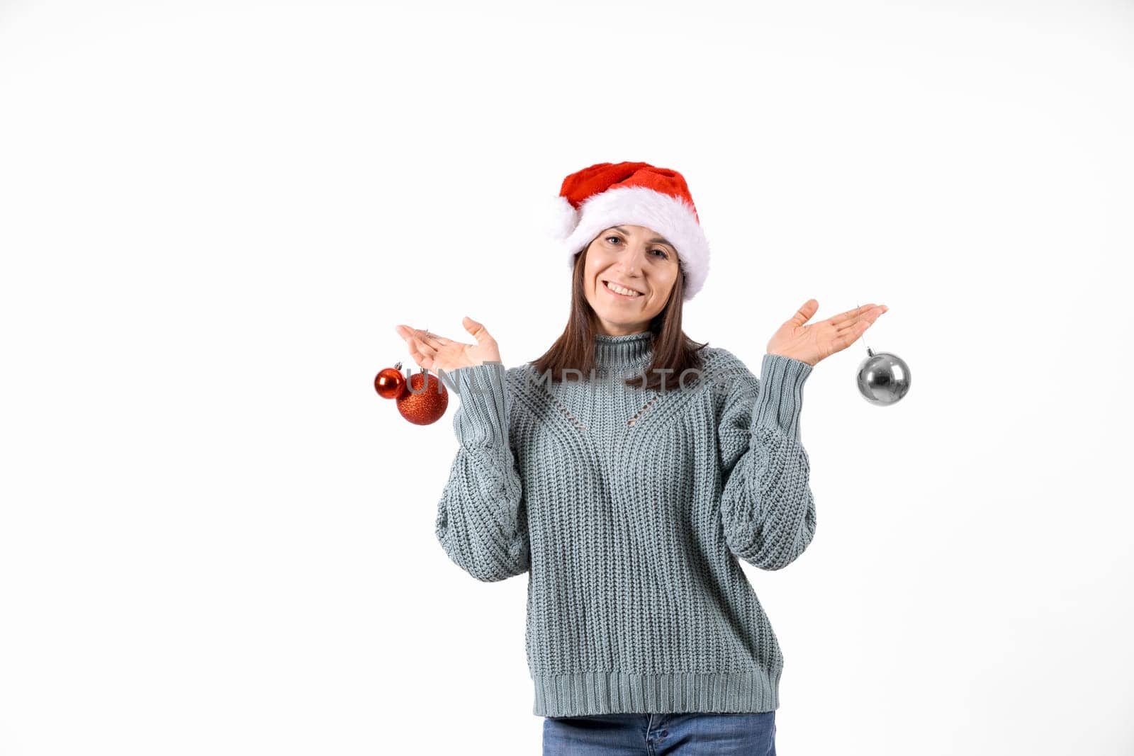 Portrait happy woman in santa hat and sweater holding red balls for Christmas tree on a white background