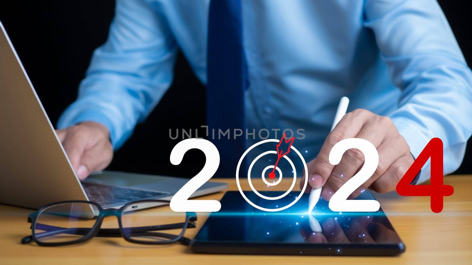 Stock trading. Finance. Investment. Growing business. Businessman in suit pointing with pen at tablet screen and lettering 2024 showing concept of setting goals and business growth in 2024 by Unimages2527