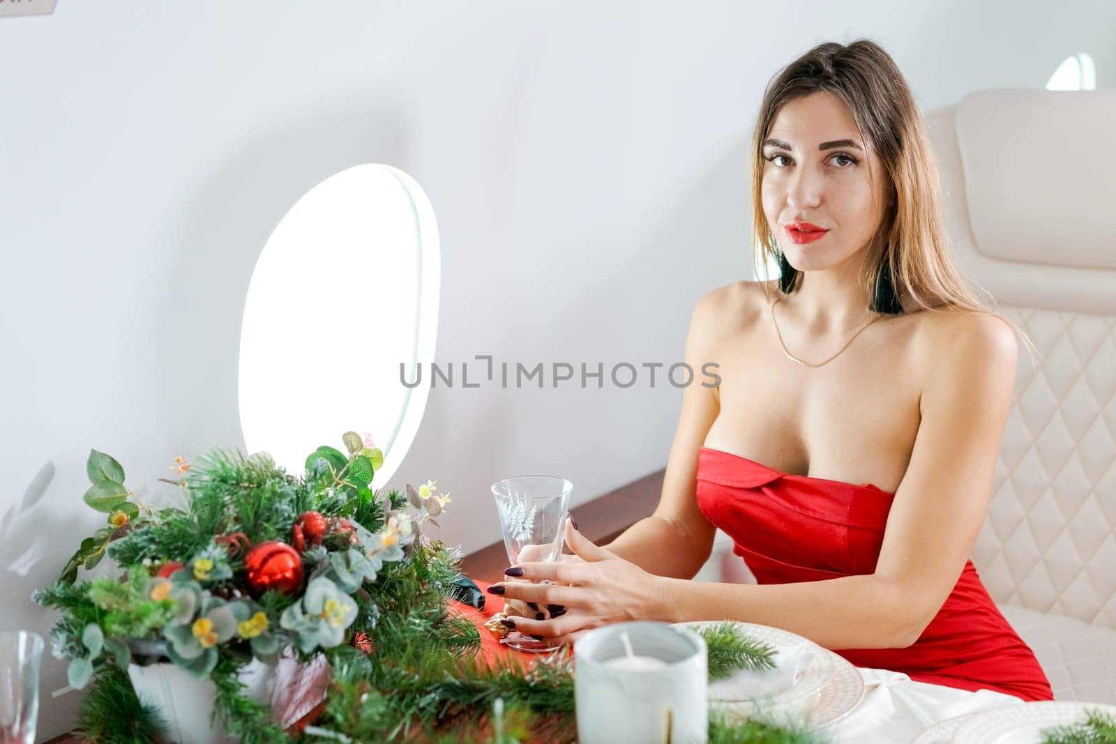 woman sits in private jet by illuminator, decorated for Christmas, New Year's Eve flight, holiday and travel concept by EkaterinaPereslavtseva