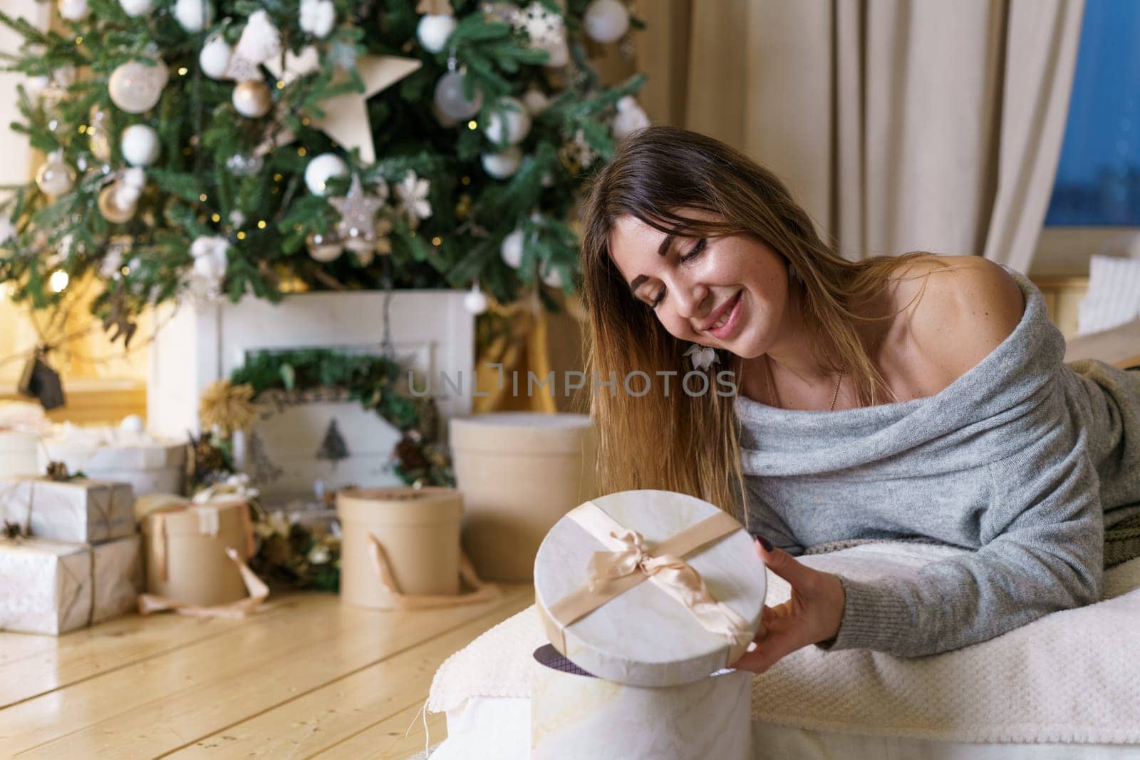 Beautiful caucasian woman lying on bed with gift in her hands, looking and by EkaterinaPereslavtseva