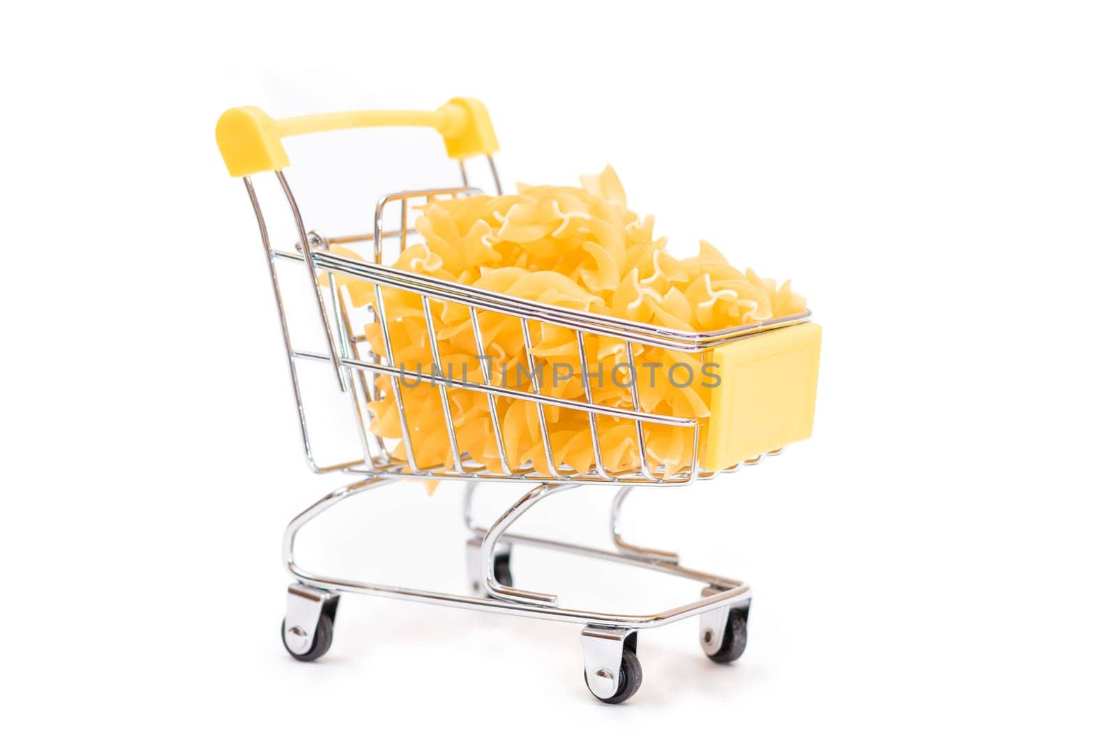 Uncooked Fusilli Pasta in Small Shopping Cart Isolated on White Background. A Crisis: Buying Cheap Food. Classic Dry Spiral Macaroni. Italian Culture and Cuisine. Raw Pasta - Isolation
