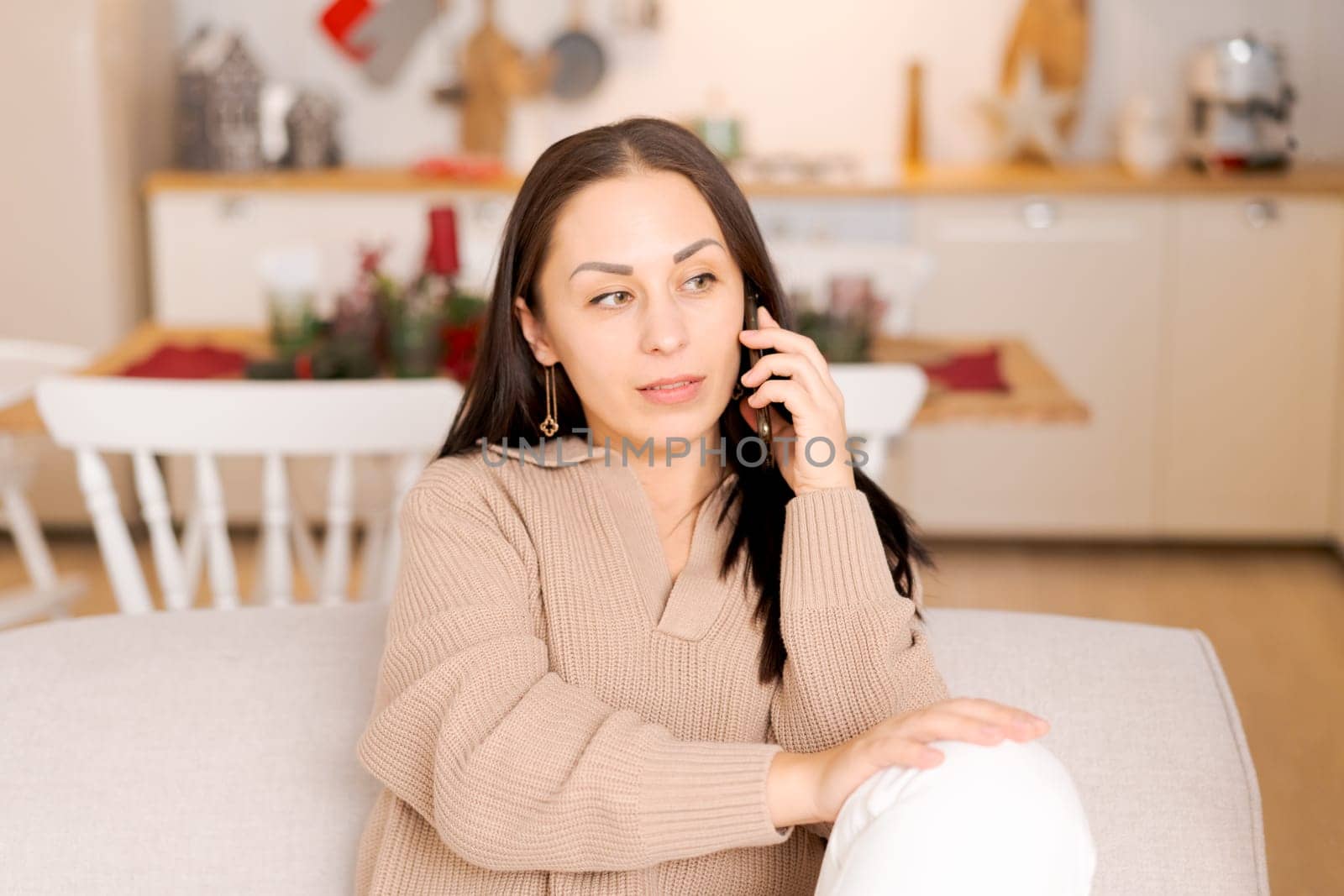 Cute woman using smartphone to call family on Christmas Eve. Talks to relatives on the phone to celebrate the holiday remotely. Communication for adults