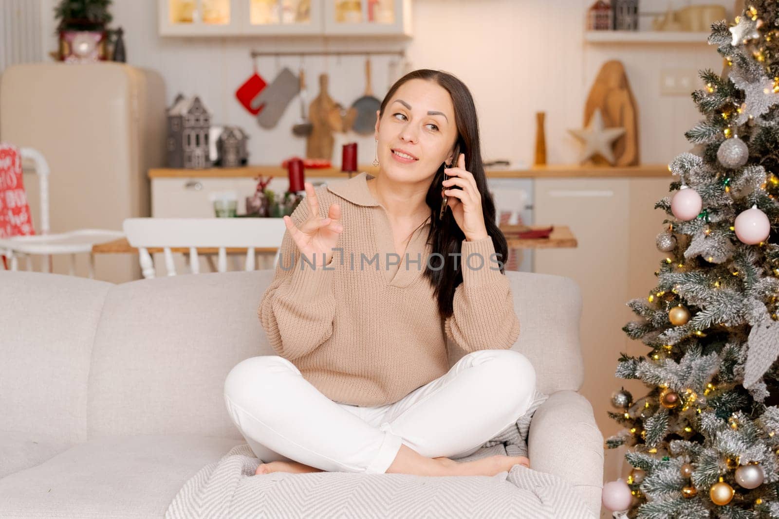 Cute woman using smartphone to call family on Christmas Eve. Talks to relatives by EkaterinaPereslavtseva