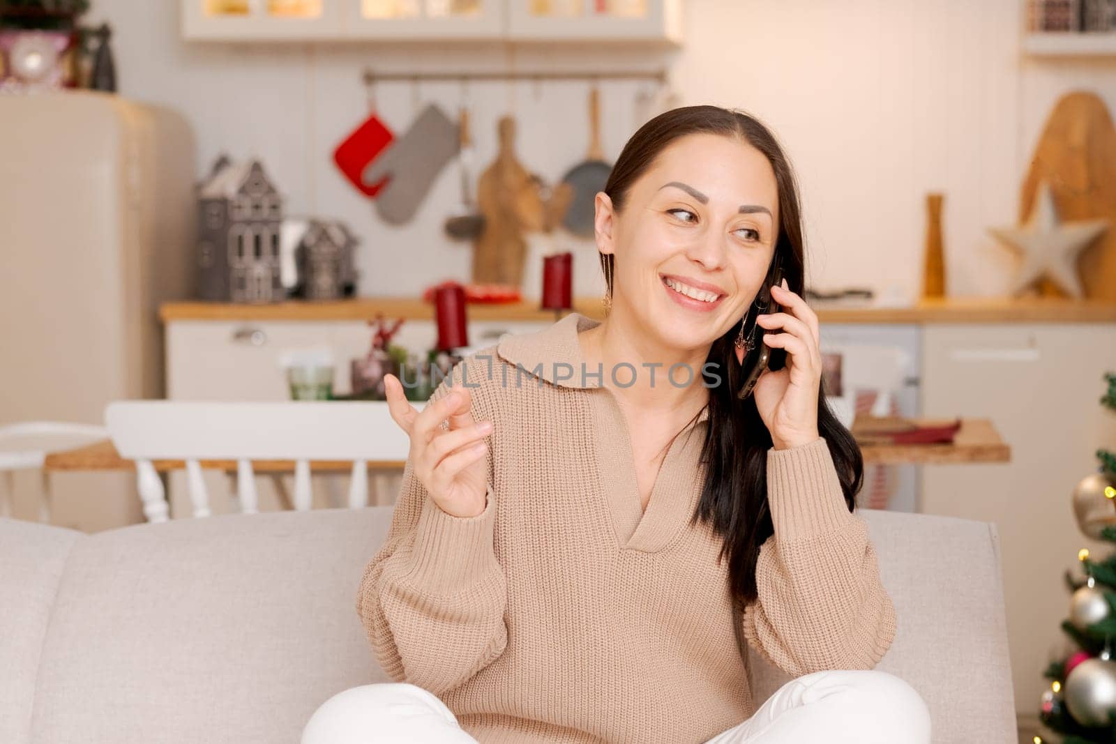 Happy woman sits on couch holding cell phone, using cellular technology by EkaterinaPereslavtseva