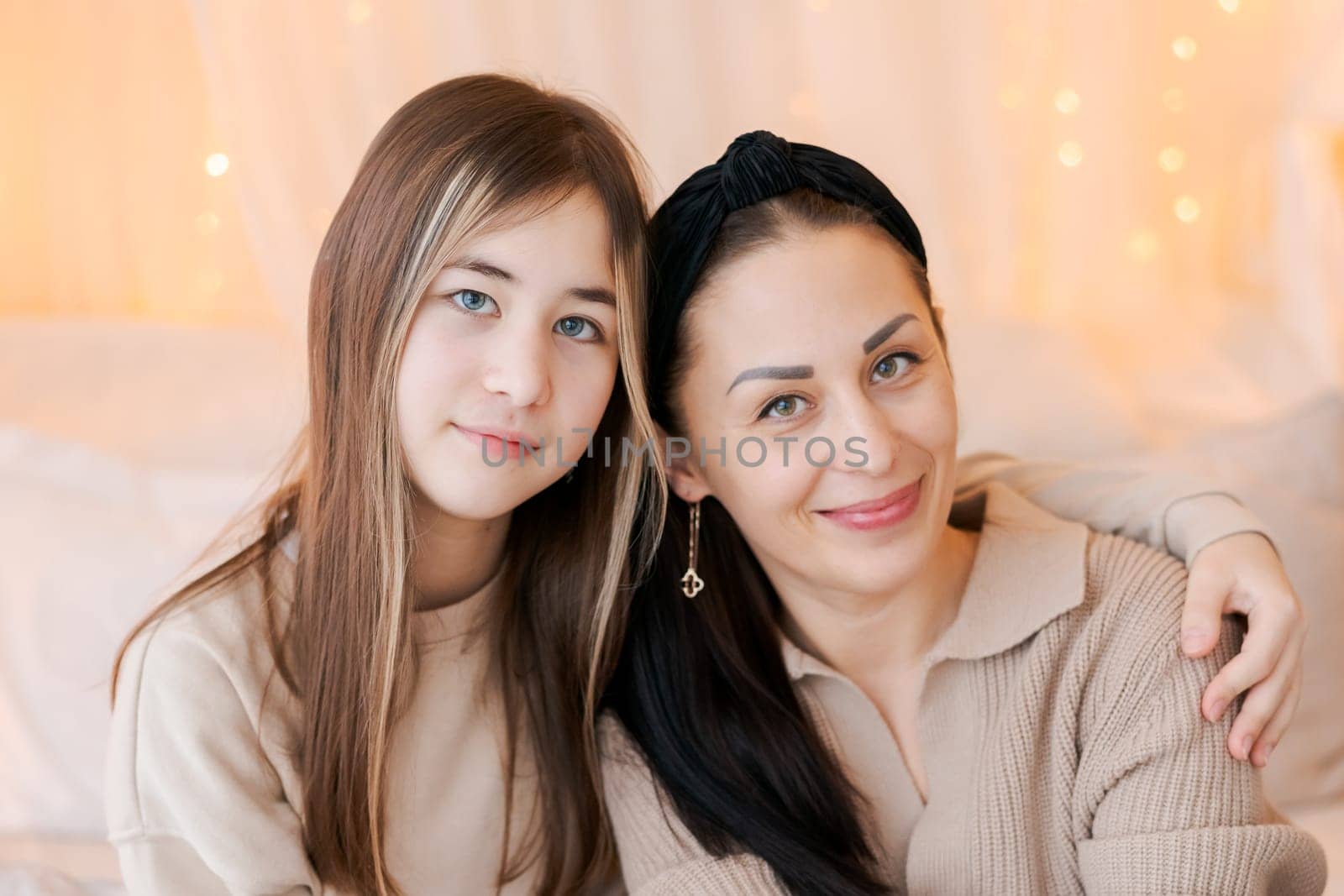 Happy mom and daughter cuddle on bed in decorated bedroom on Christmas Eve by EkaterinaPereslavtseva