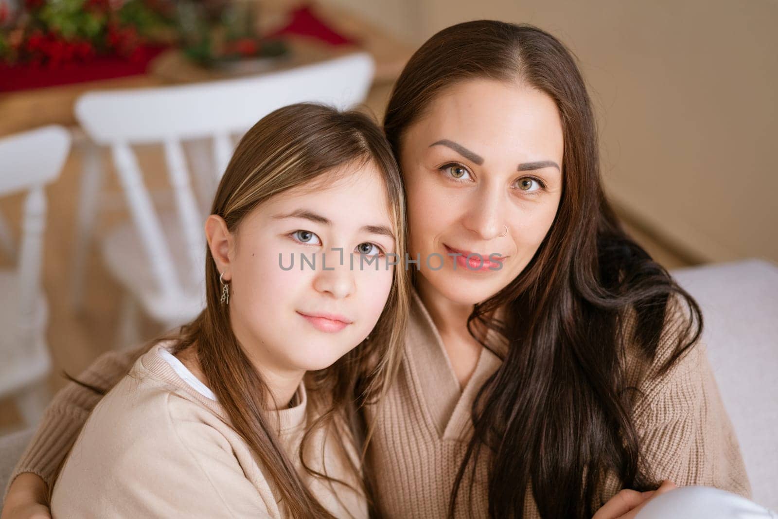 Mom and daughter sitting on couch cuddled together waiting for Christmas to arrive