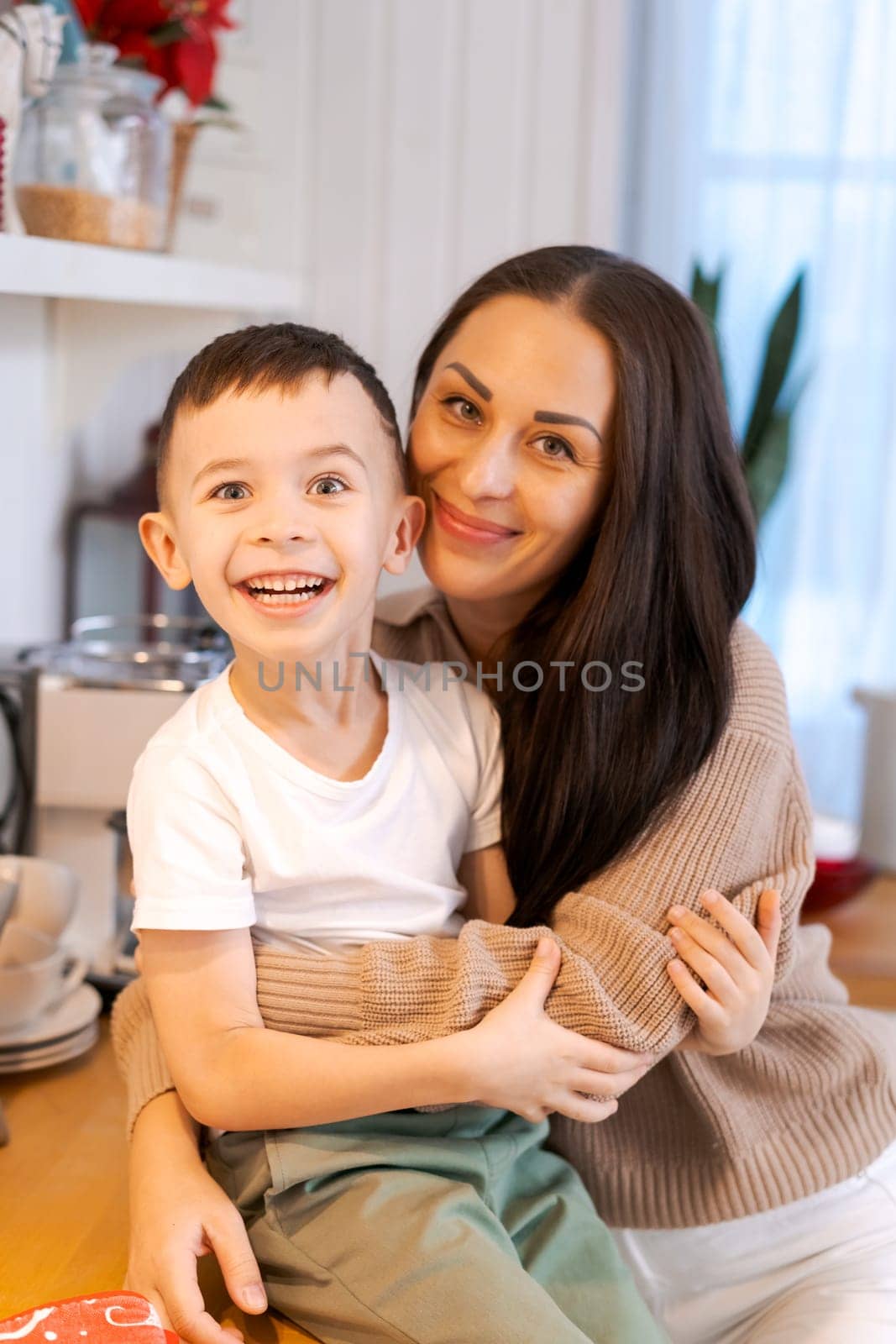 Fun mom and son playing in kitchen, happy spending time on Christmas Eve by EkaterinaPereslavtseva