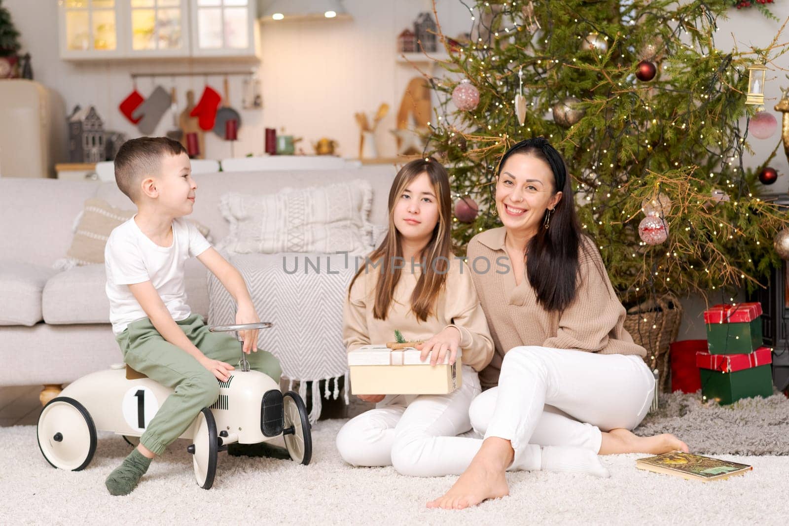 Happy family in decorated house at Christmas sitting on floor against couch and Christmas tree. Selective focus