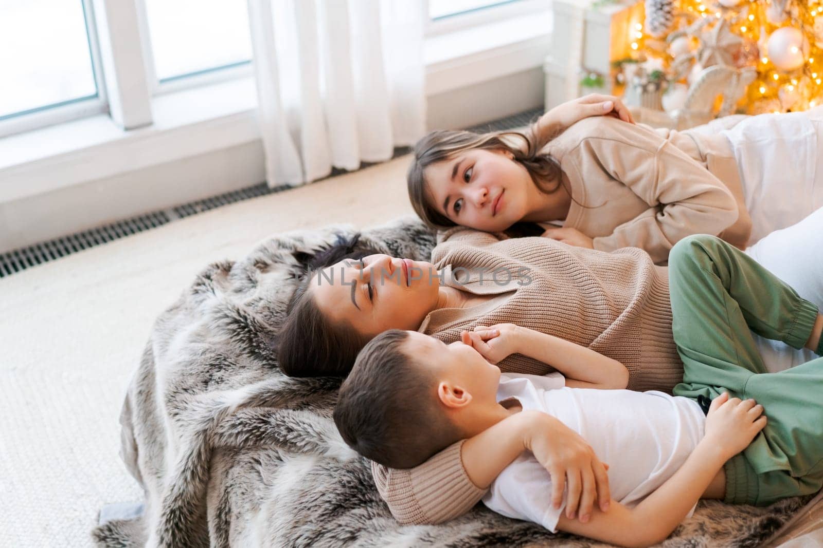 Happy family mom and two kids lying on bed waiting for Christmas and laughing. by EkaterinaPereslavtseva