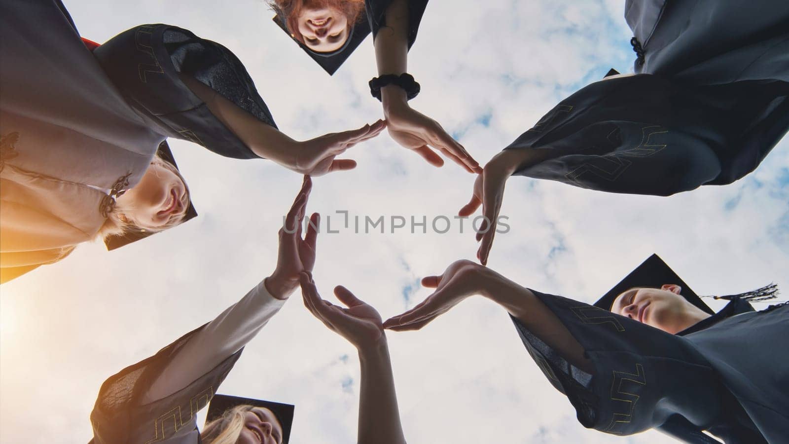 College graduates make a circle of their hands