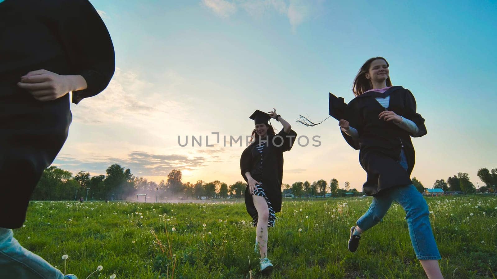 College graduates run at sunset in the evening. by DovidPro